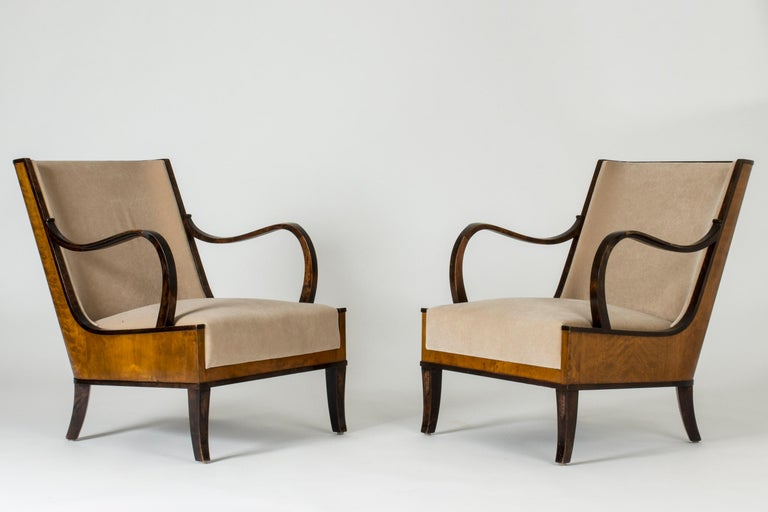 Pair of elegant lounge chairs by Erik Chambert, with distinct silhouettes and clean, curved lines. Made from stained wood, upholstered with velvet.
