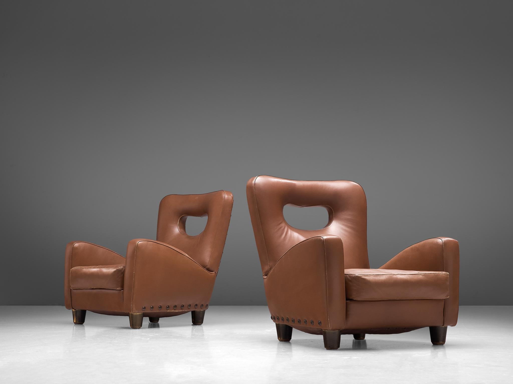 Giovanni Gariboldi for Colli, pair of lounge chairs, leather, wood and bronze nails, Italy, circa 1950.

A rare pair of sturdy lounge chairs in cognac leather designed by Giovanni Gariboldi. The easy chairs show voluptuous, round lines. The most