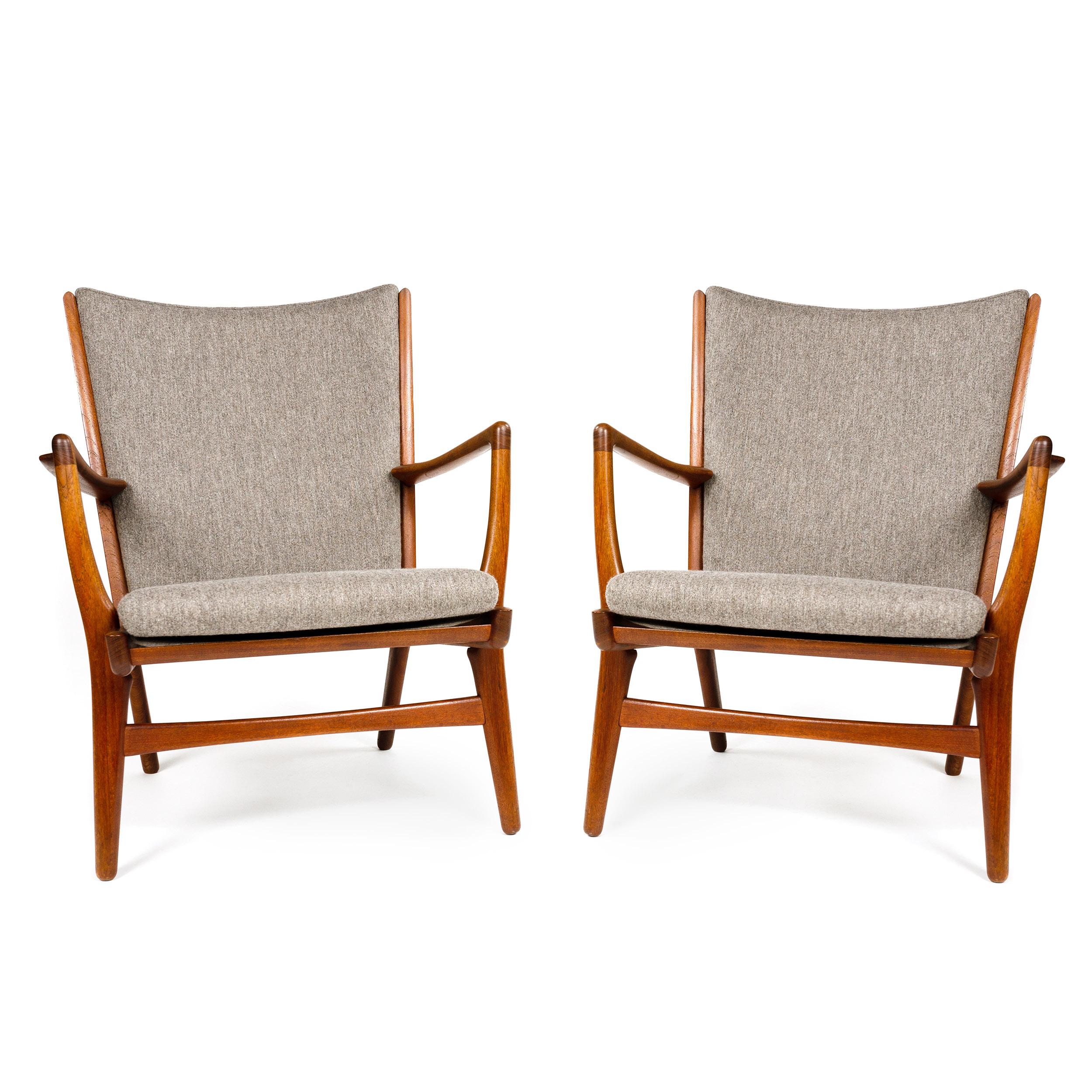 A set of two (2) Scandinavian Modern lounge chairs designed by Hans Wegner. Each featuring sinuous solid teak frames and grey wool Savak upholstered seat and back.
 