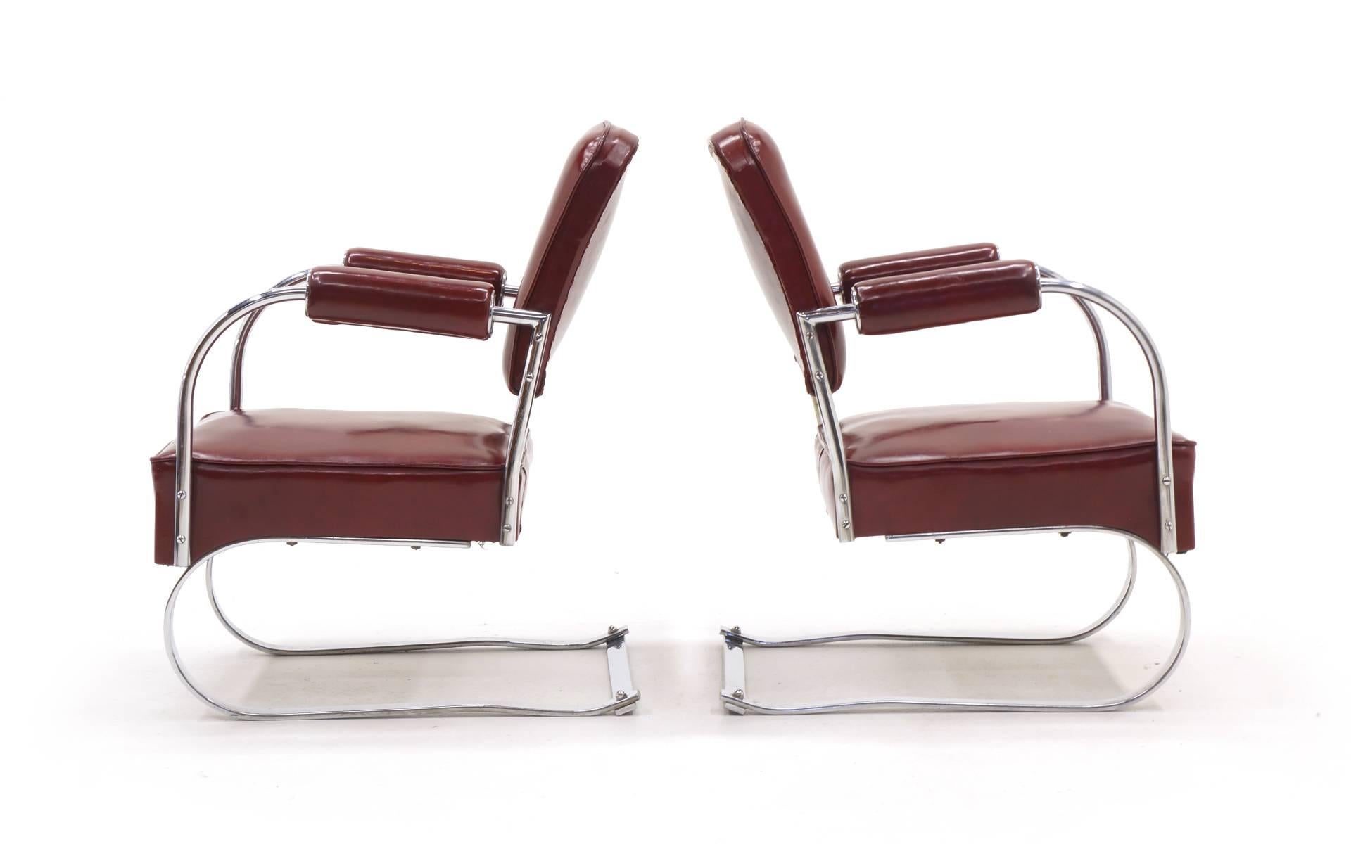 Pair of 1940s tubular chrome and completely original red vinyl lounge/club chairs designed by KEM Weber. These were covered in storage for the past 40 years. There are no tears or obvious wear to the original vinyl.