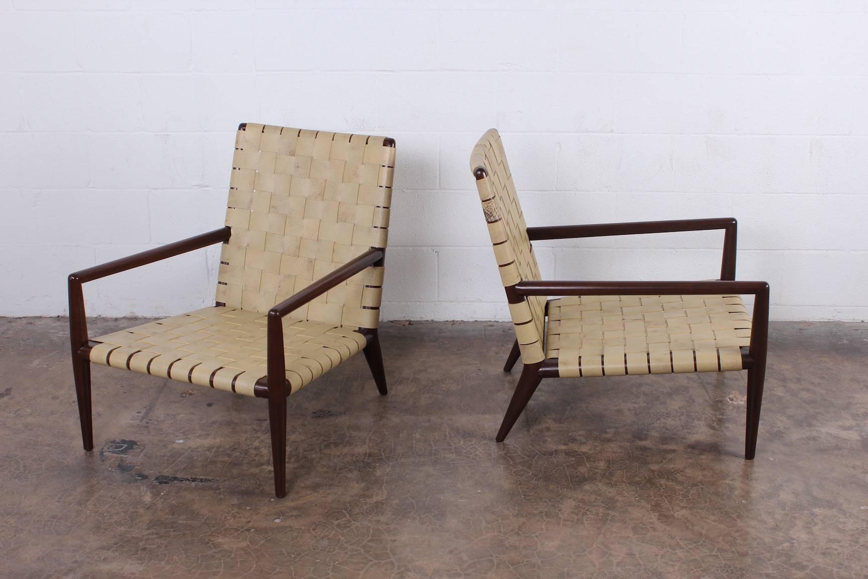 A pair of leather strapped lounge chairs with walnut frames. Designed by
T.H. Robsjohn-Gibbings for Widdicomb.