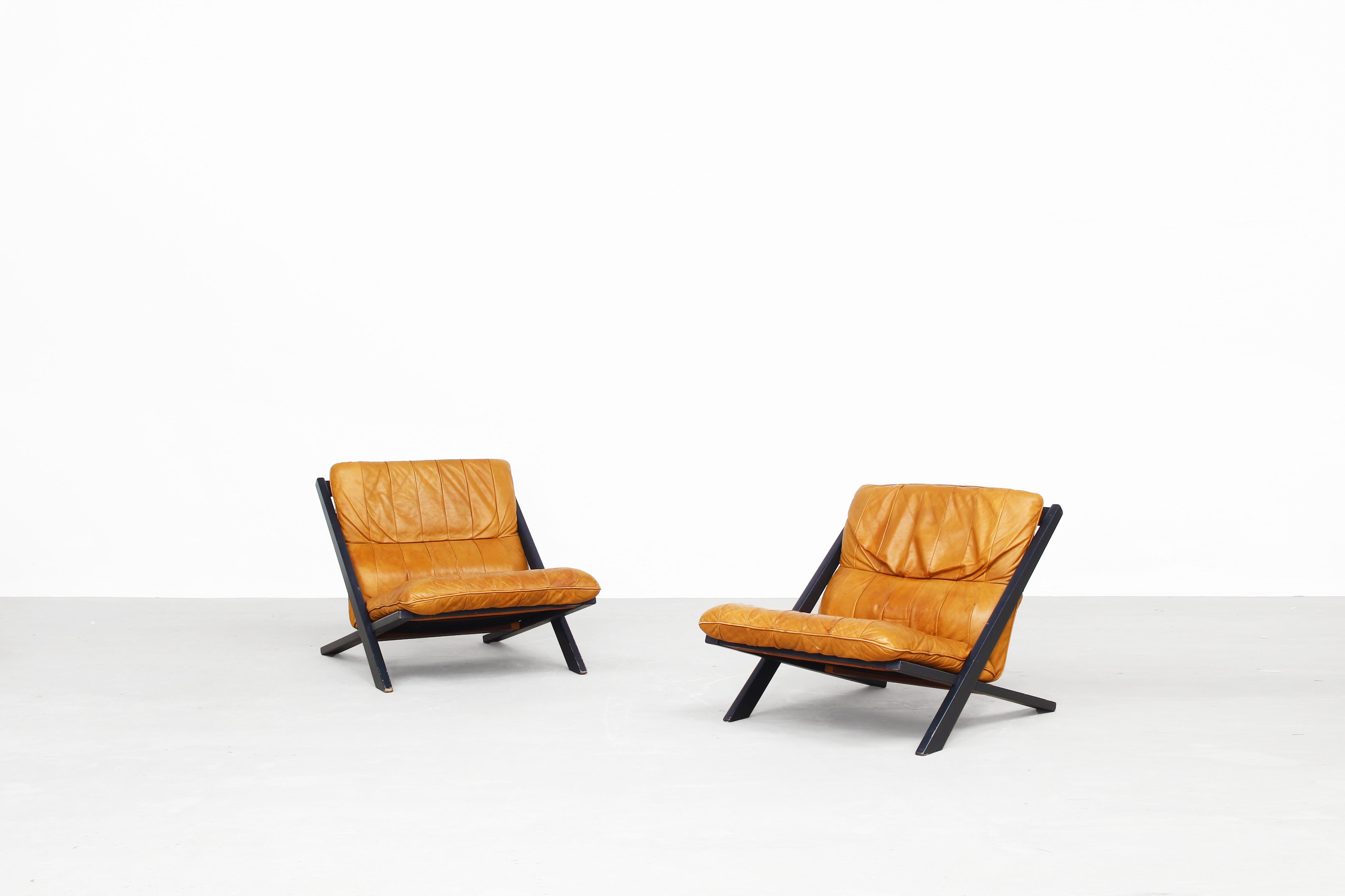 Very beautiful pair of lounge chairs designed by Ueli Berger for De Sede, 1970s, Switzerland.
Both chairs come in a great original condition with a great patinated leather in brown-cognac. Without any damages, repairs - ready for use. Two matching