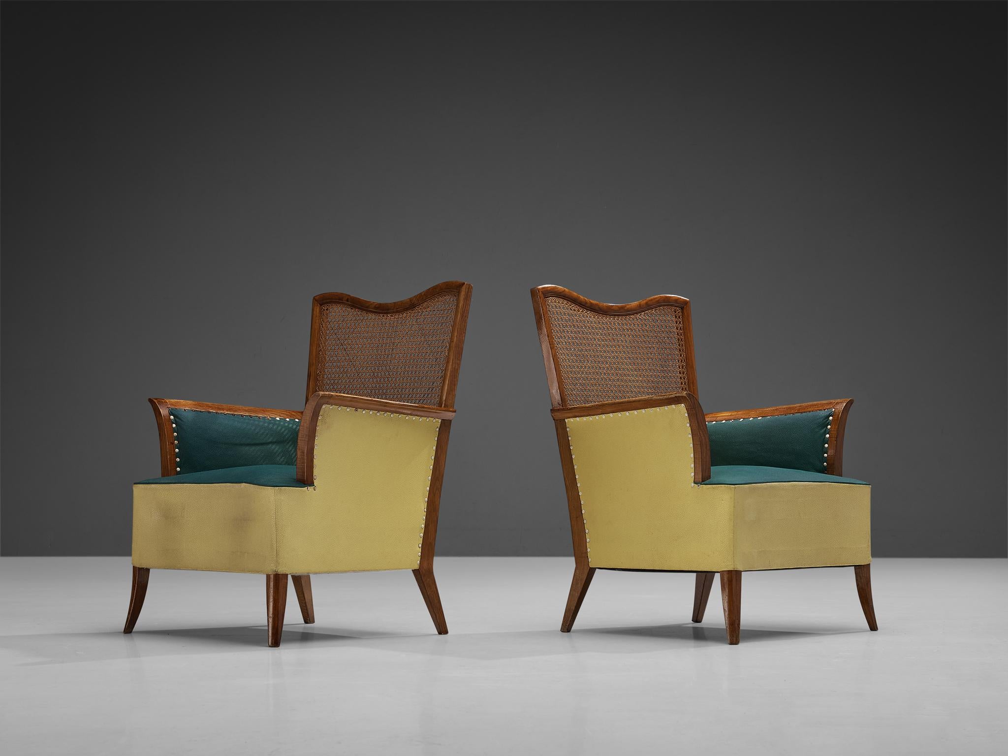 Pair of easy chairs, ash, cane, leatherette, metal, Spain, 1950s. 

Joyful pair of Spanish lounge chairs with soft organic lines. These chairs feature a stained ash frame of which a dynamic grain pattern comes through. The backrest is made of woven