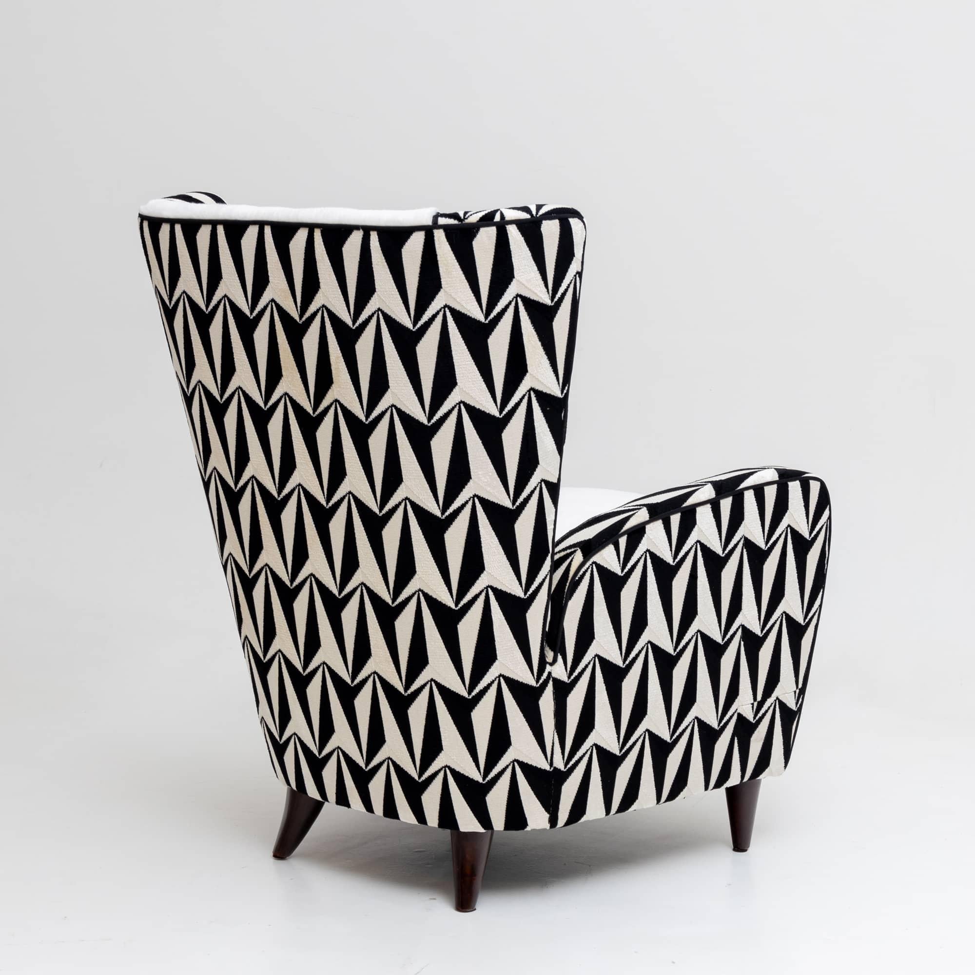 Pair of lounge armchairs with large trapezoidal backrests on conical legs. The armchairs have been reupholstered and covered with a high-quality black and white patterned fabric. The seat cushion and the backrest are covered with a white faux fur