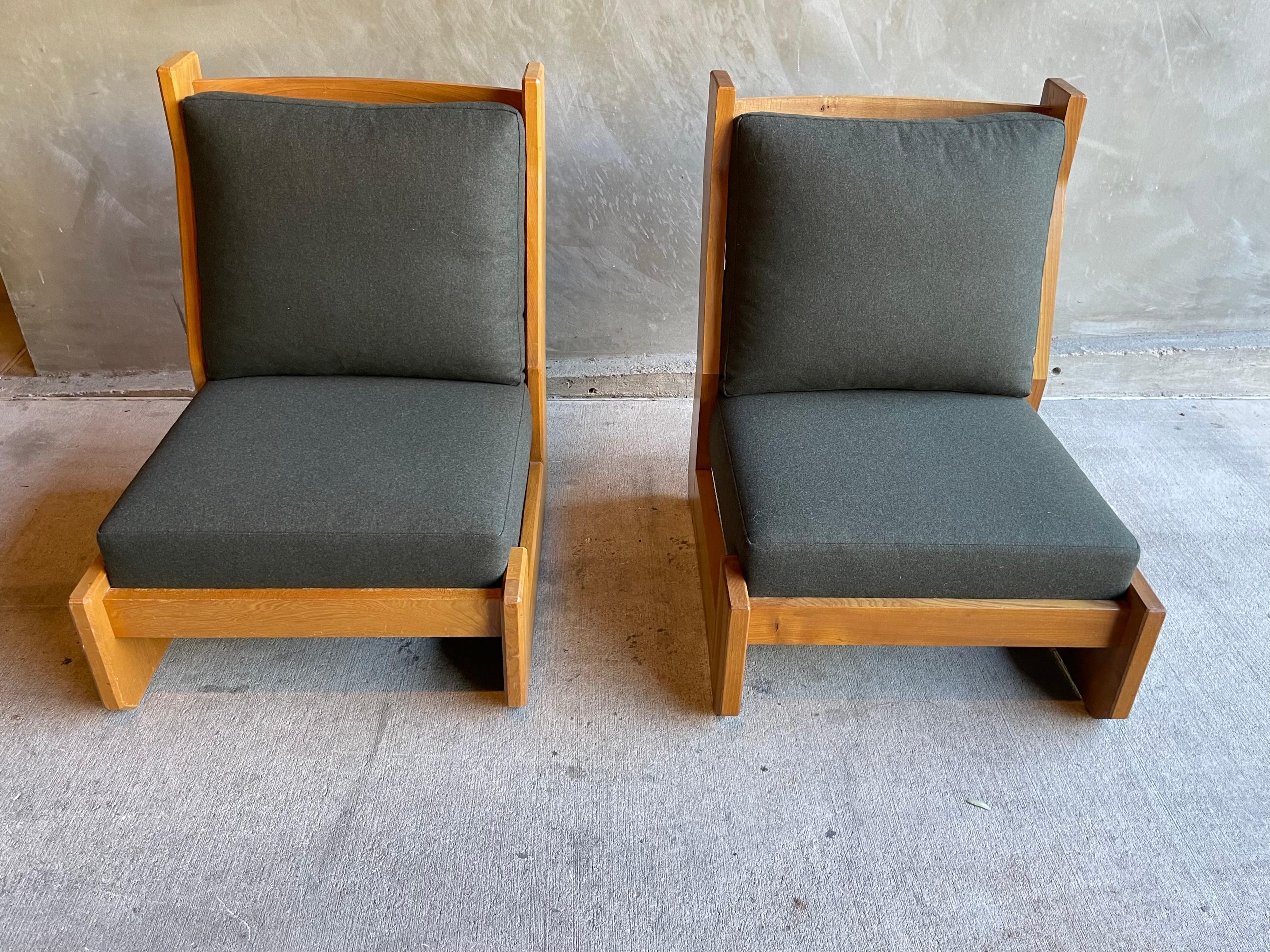 Pair armless lounge chairs by collectible maker, Maison Regain, with solid elm frames. Notice the handsome slatted backs. Newly upholstered with foam and down cushions in luxurious Chiavasso wool fabric. Color is a dark grayish green. Very