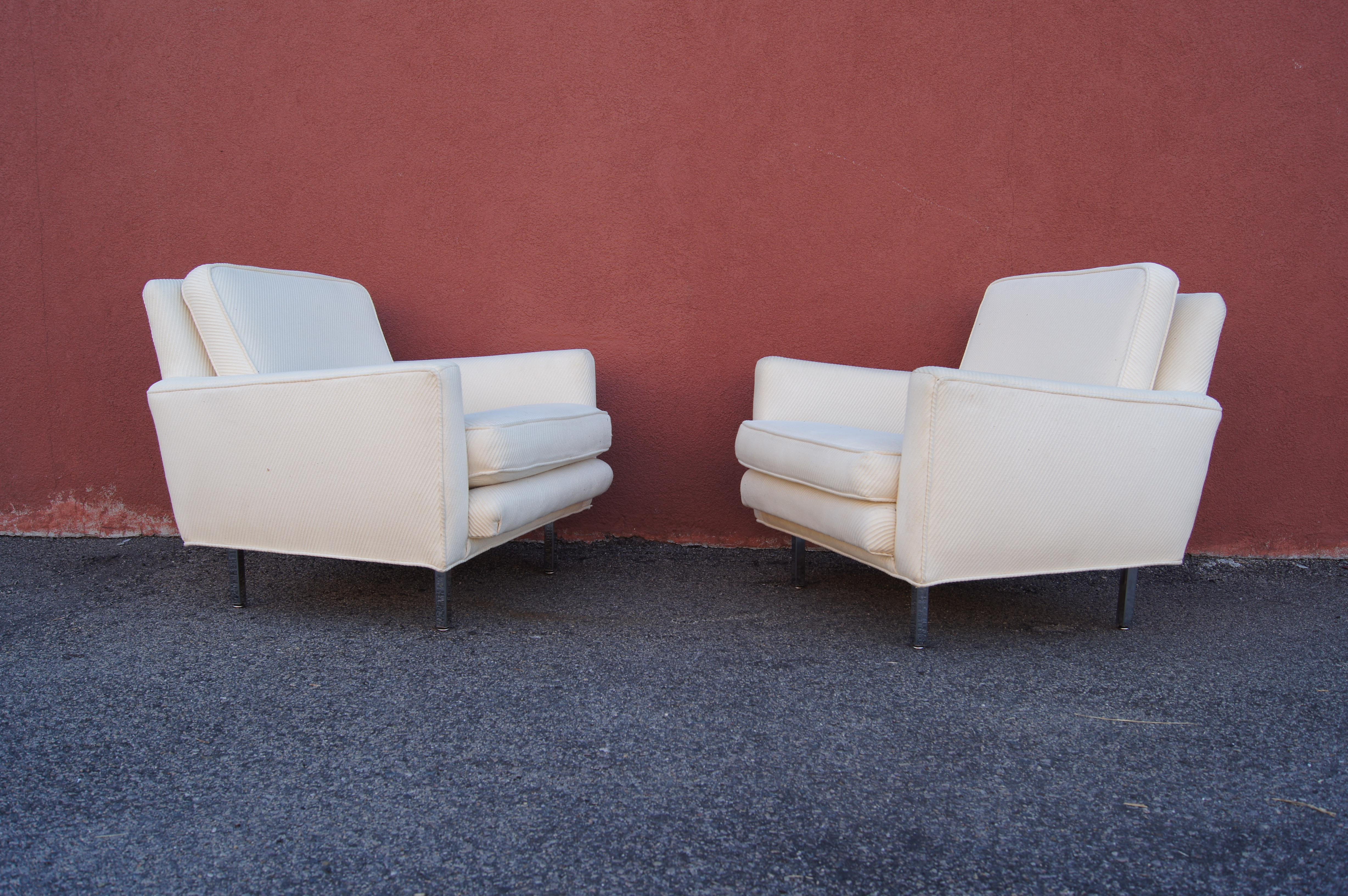 Designed by George Nelson, this pair of clean-lined model 5681 lounge chairs were produced by Herman Miller from 1956 to 1967. Raised on square chrome legs, the upholstered club seat offers deep comfort with a sloped back, high angled arms, and