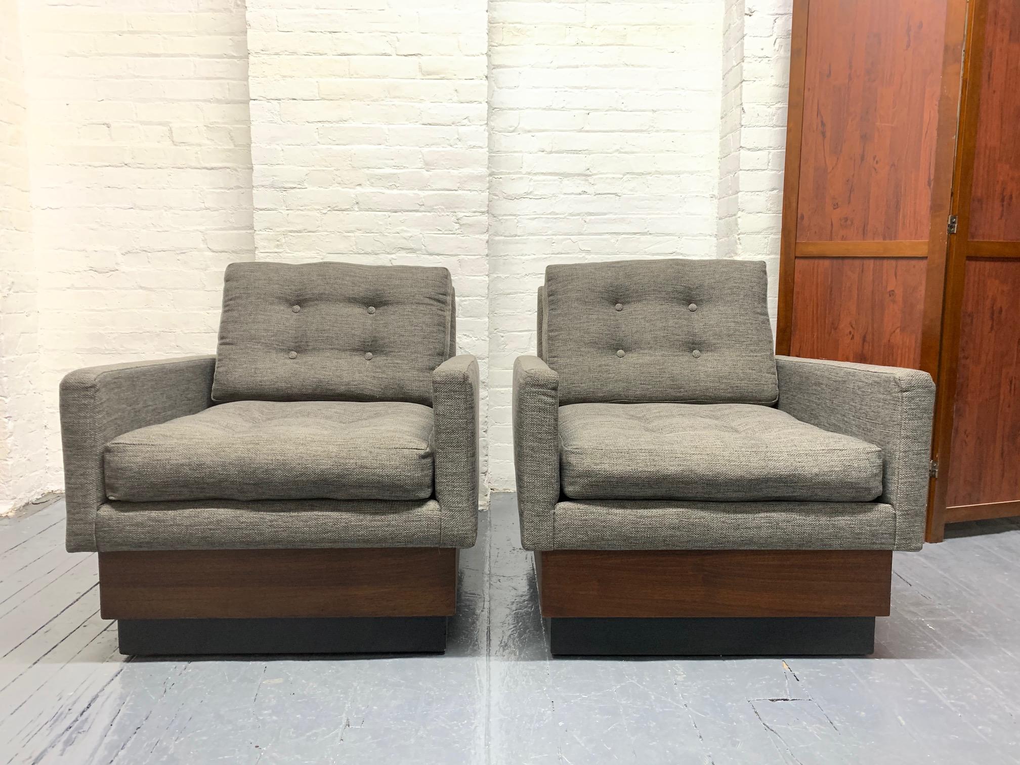 Pair of Mid-Century Modern lounge chairs. Has a walnut and black lacquered plinth base. Loose, tufted cushioned seat and back.