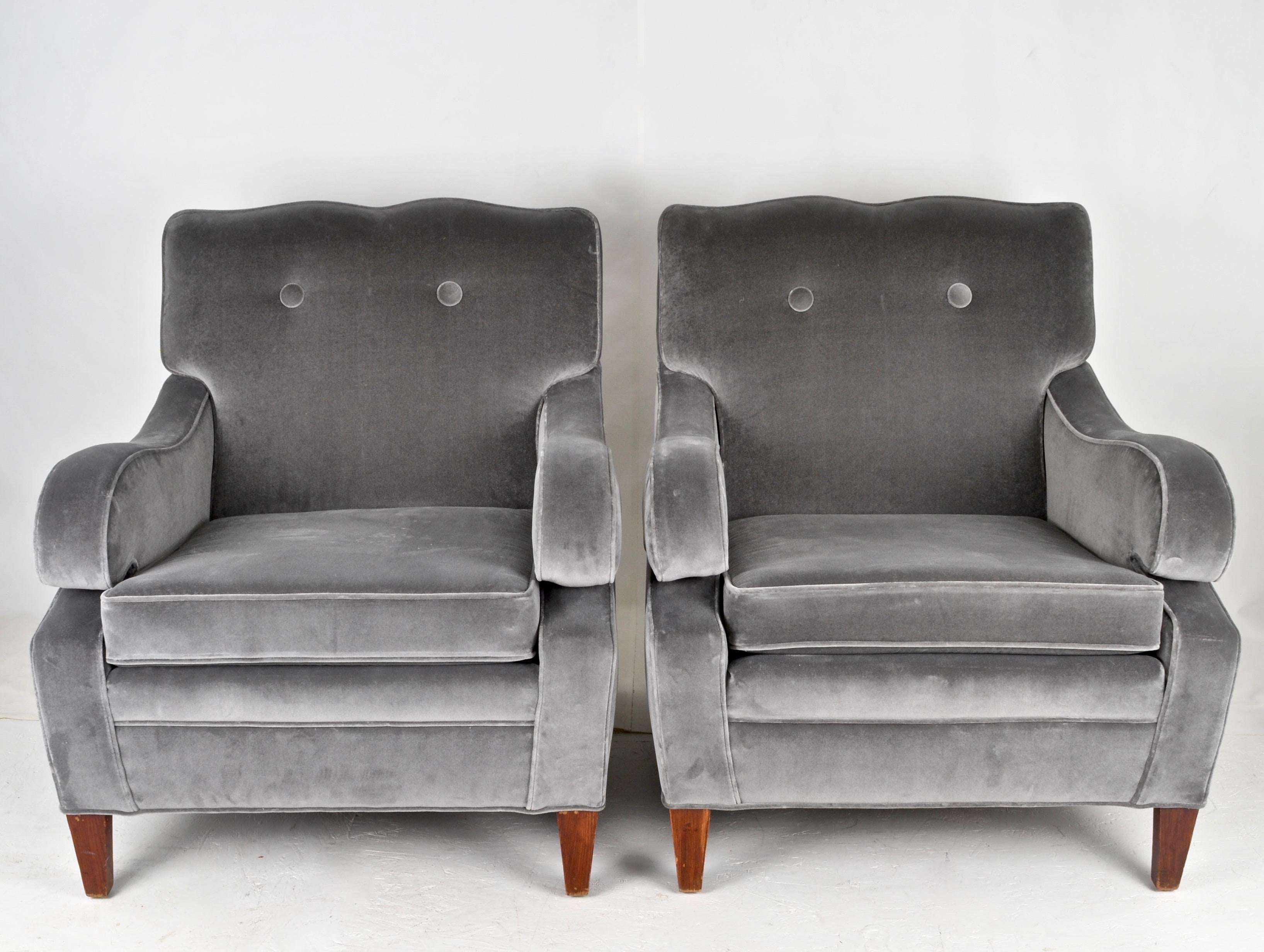 Newly upholstered in grey velvet, a pair of club chairs with stylish details. Note arms and back with typical Dorothy Draper style curves. Large scale, very comfortable. Seat cushion is firm but not hard.