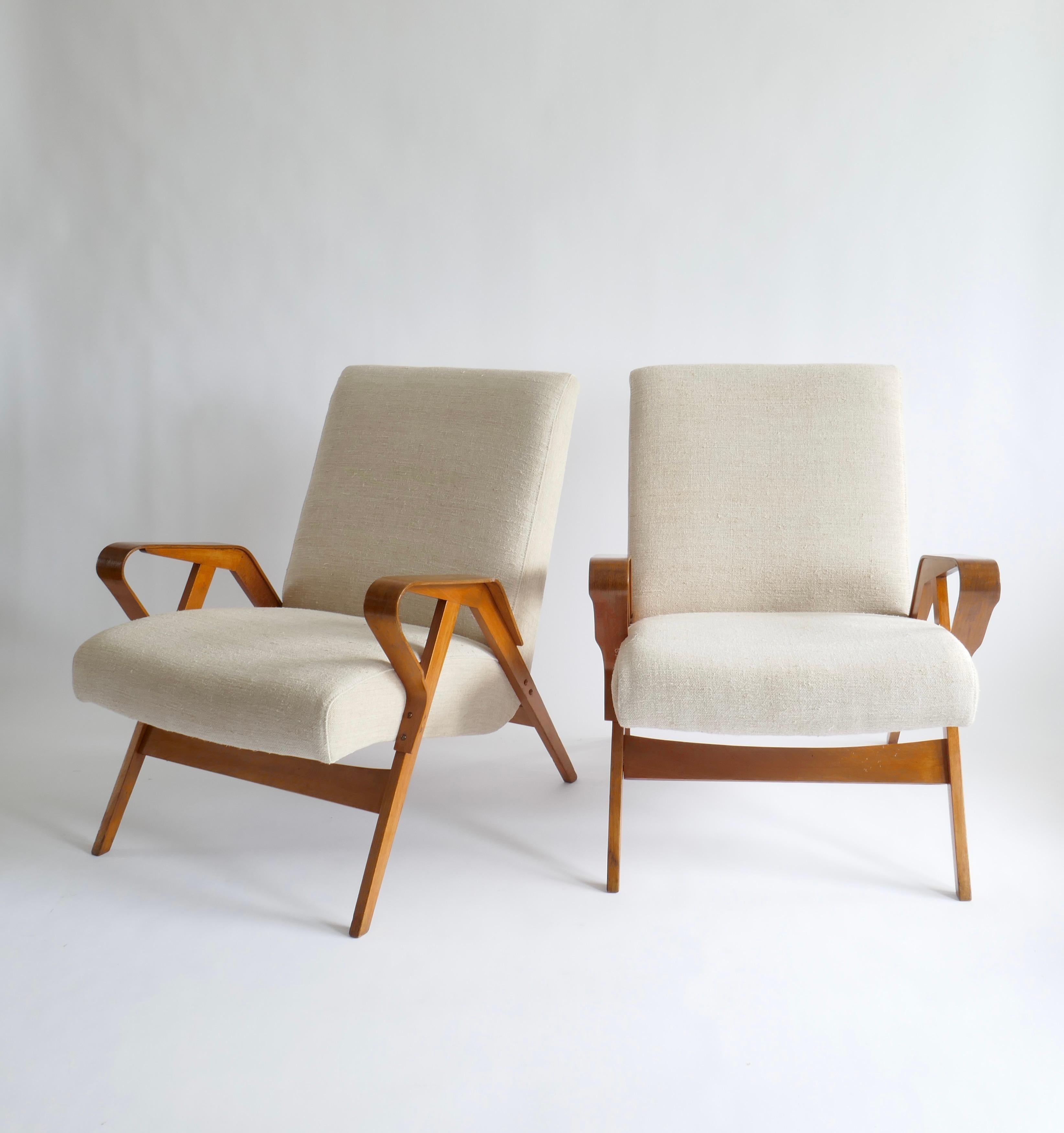 A beautiful pair of Mid-Century Modern armchairs. Sculptural wood frame hosts a comfortable seating with slightly inclined back rest and a deep seat.
Upholstered in a beautiful vintage off white linen they are perfect in any type of room decor 
In