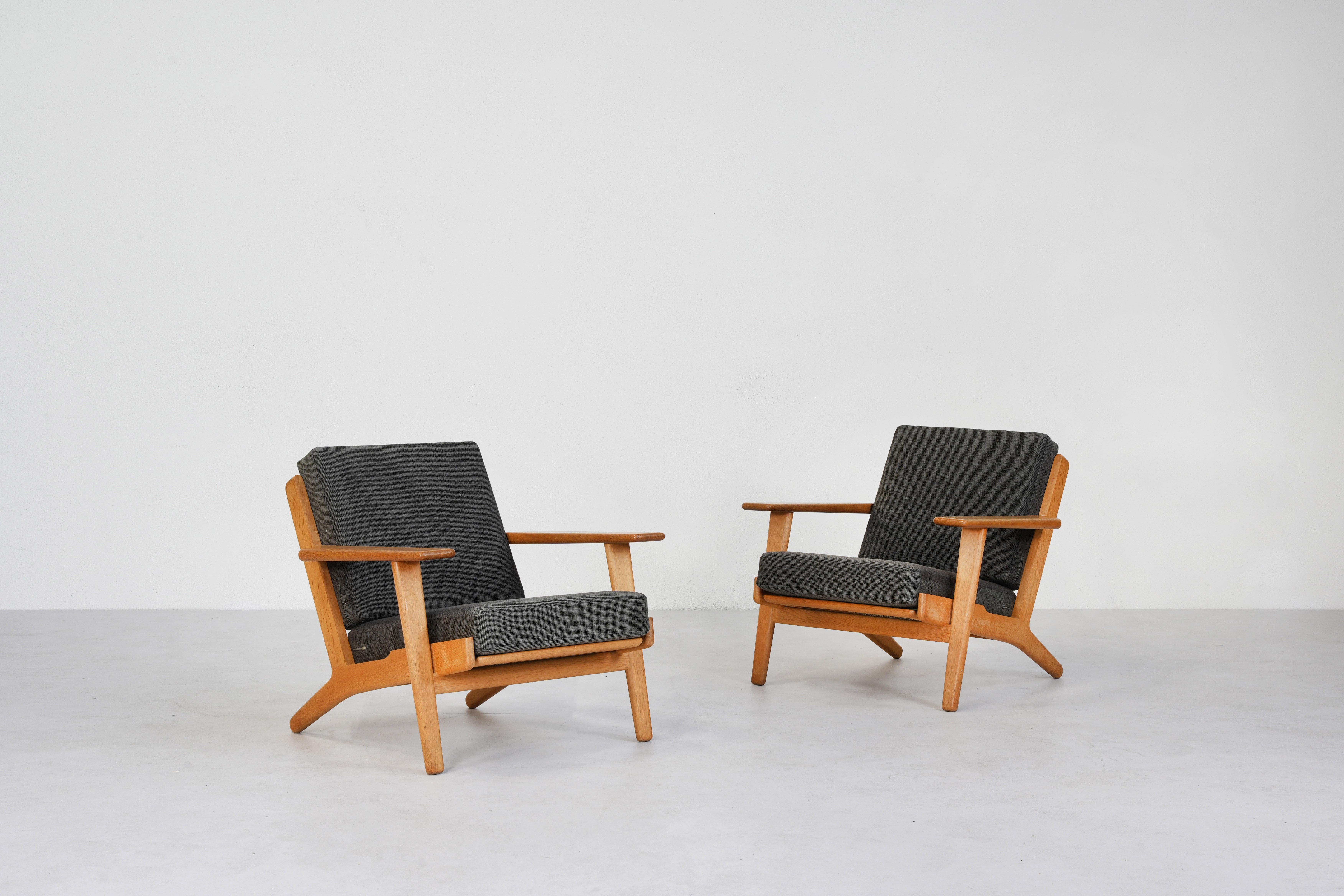 A beautiful pair of Lounge Easy Chairs designed by Hans J. Wegner for GETAMA GE 290, made in Denmark. These chairs are in excellent condition. The oakwood frame has developed a beautiful patina over time. The cushions, while still in good condition,