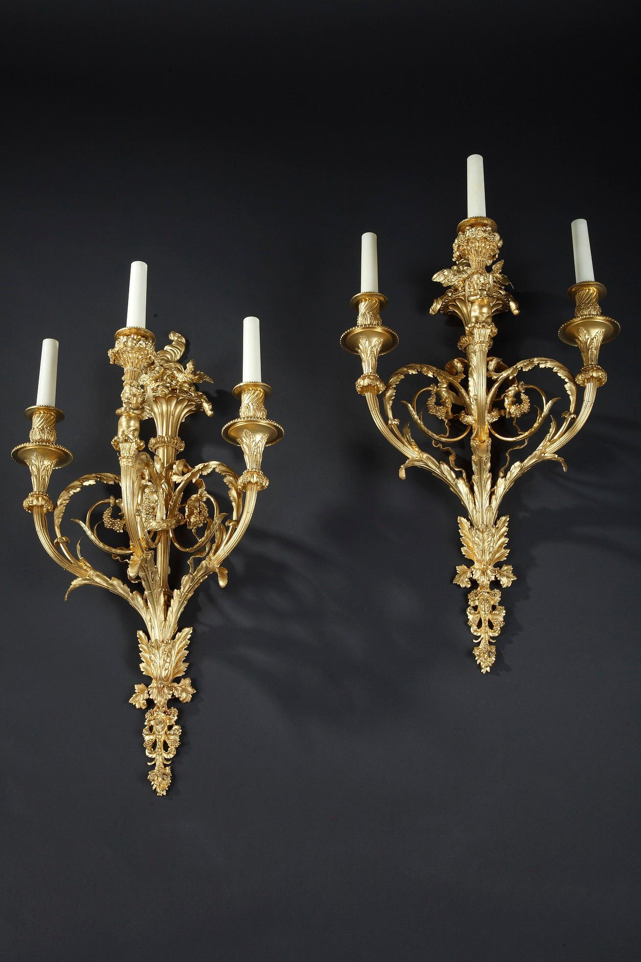 Elegantes Paar dreiflammiger Wandleuchter im Louis XVI-Stil aus gemeißelter und vergoldeter Bronze, signiert Denière.
Die in Arabesken angeordneten Zweige aus Blattwerk sind durch eine Girlande und eine Bandschleife mit dem geriffelten Schaft