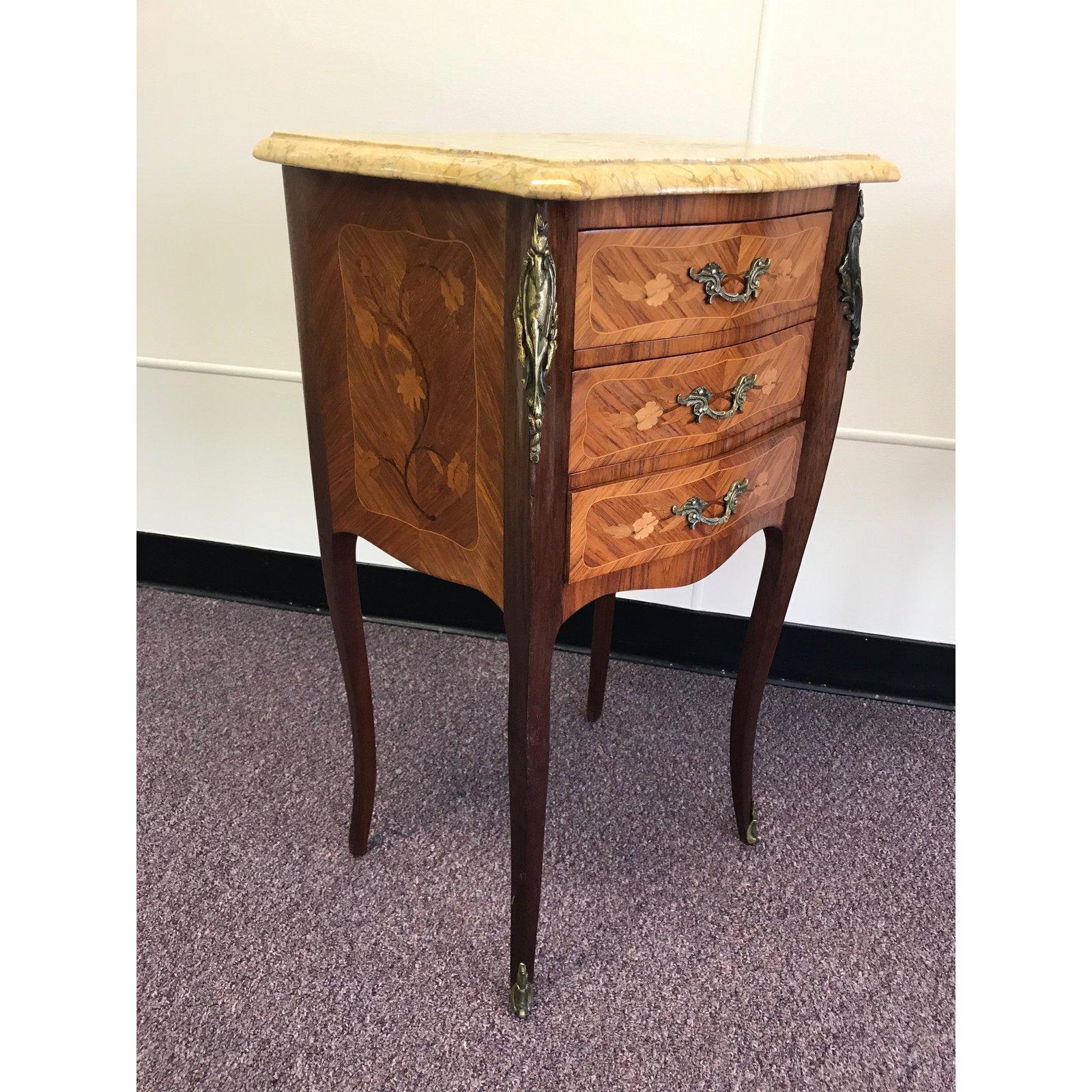 Pair of beautiful inlay French side tables or nightstands from the Brittany region of France. The three drawers are adorned with a mixed wood inlay of a floral design which compliment the original bronze drawer pulls. There are additional bronze