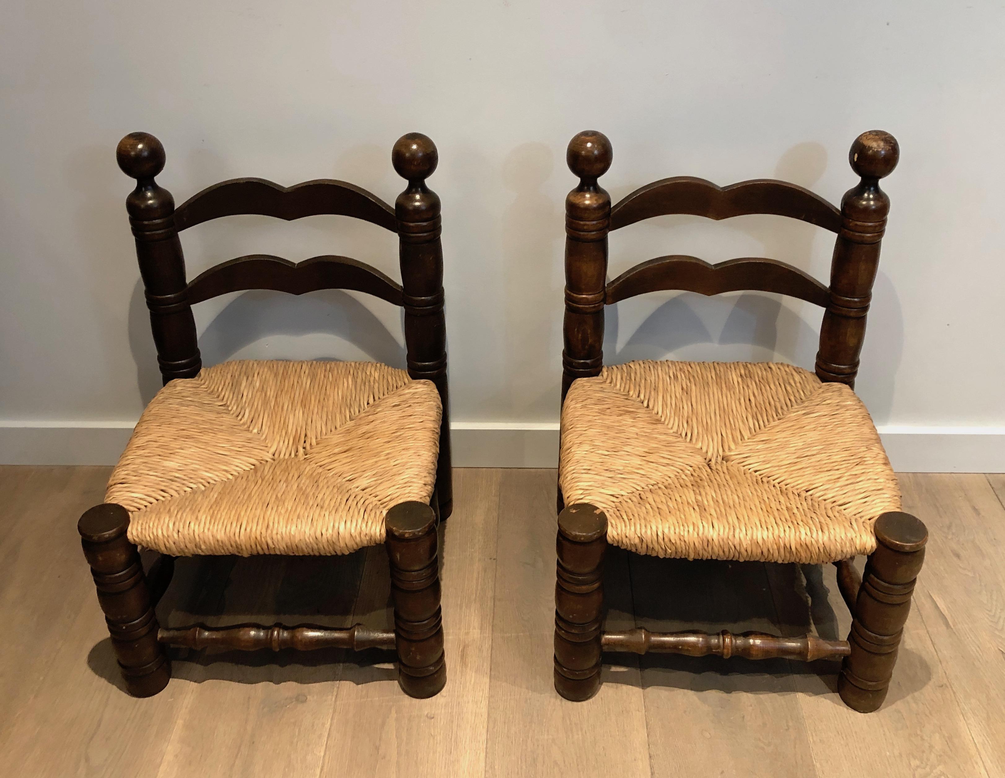 This pair of low brutalist chairs is made of carved wood and straw. This is a French work by Charles Dudouyt. Circa 1920.
