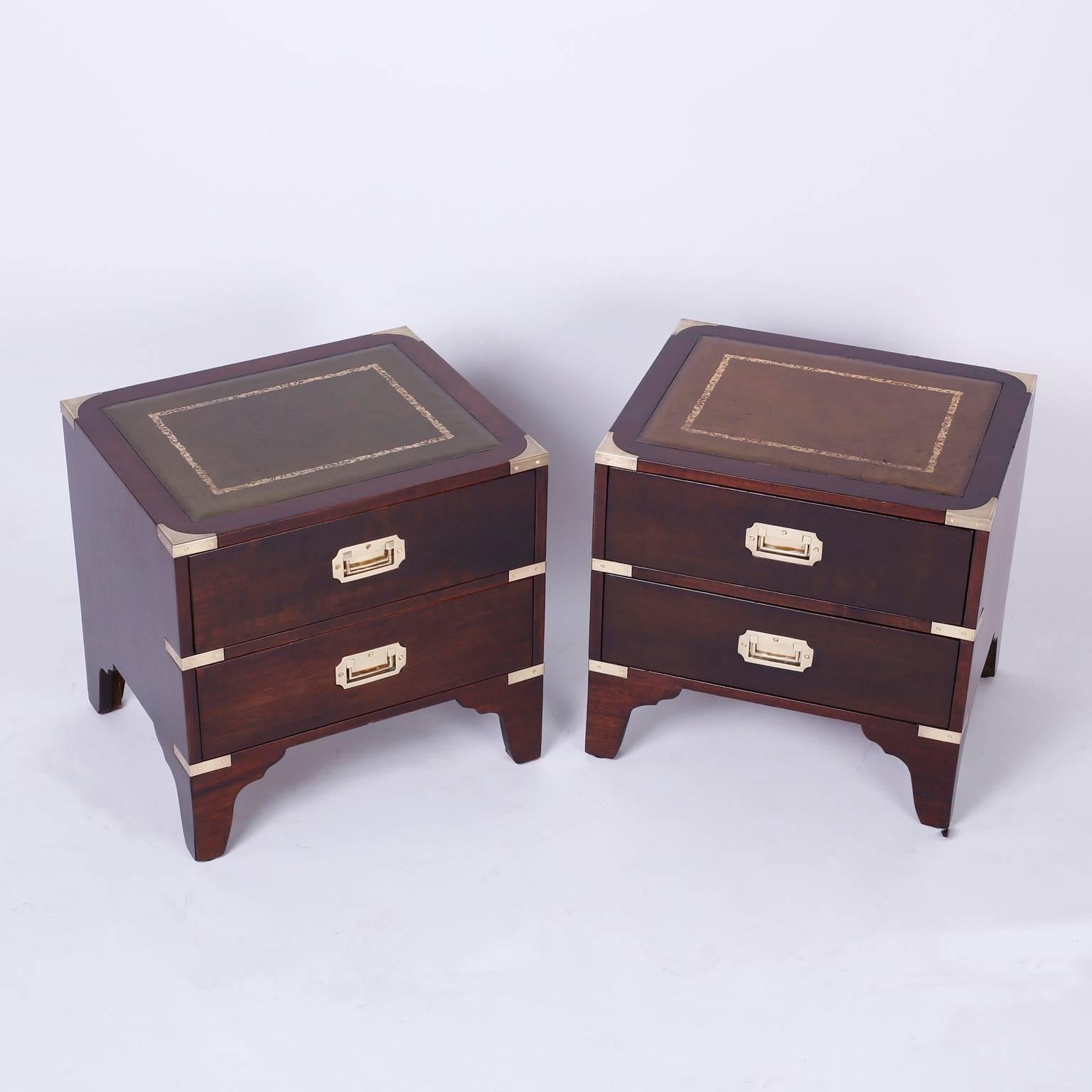 Unusual pair of low two-drawer chests or nightstands with slightly different compatible tooled leather tops, mahogany construction, and brass Campaign style hardware. All this over bracket feet, Classic timeless form.