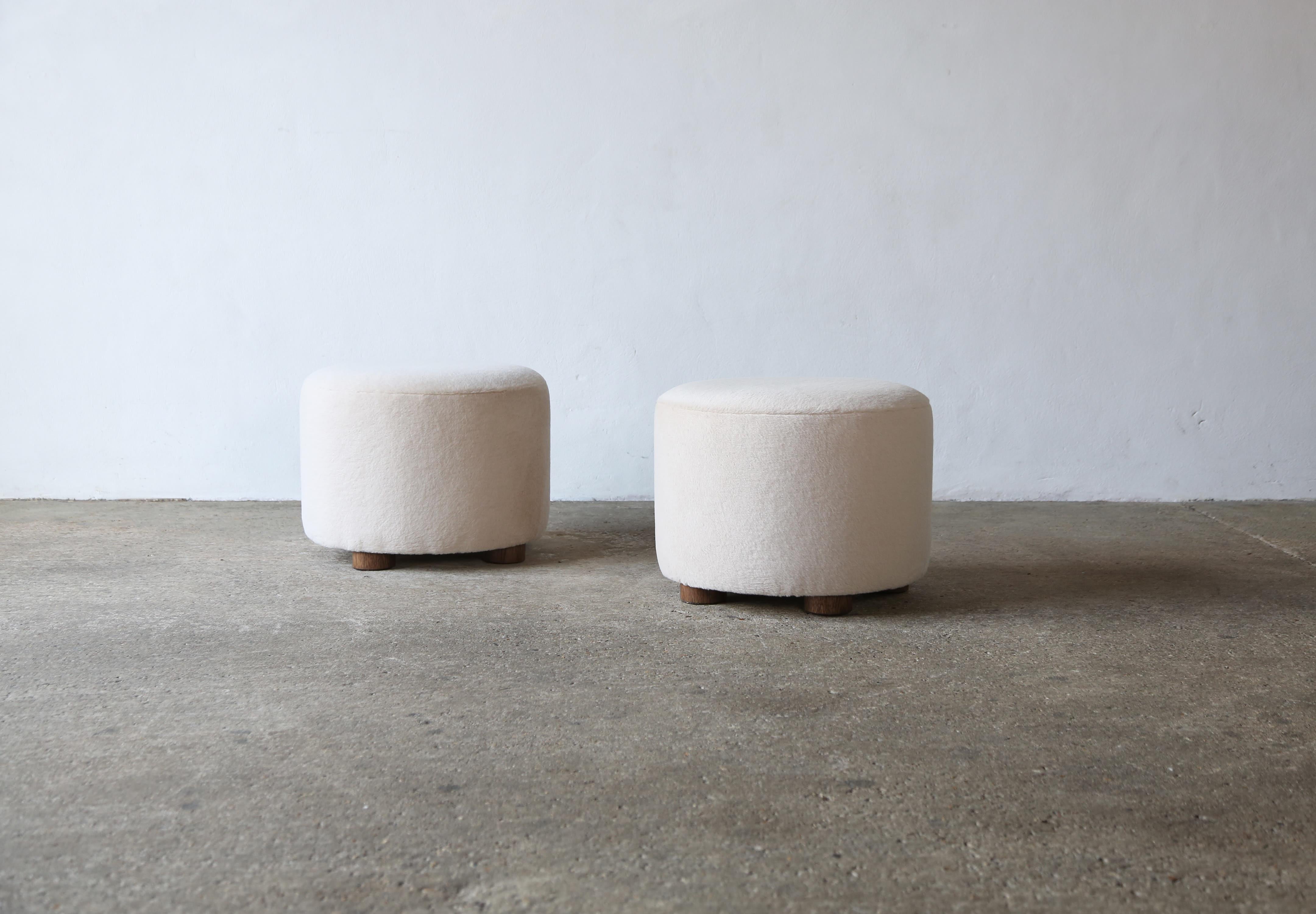 A pair of elegant, modern, low, round ottomans.  Handmade in England.  Newly upholstered in a premium, soft, pure alpaca wool fabric with solid oak feet.    Priced and sold as a pair.  Custom sizes and fabric options available.    Fast shipping