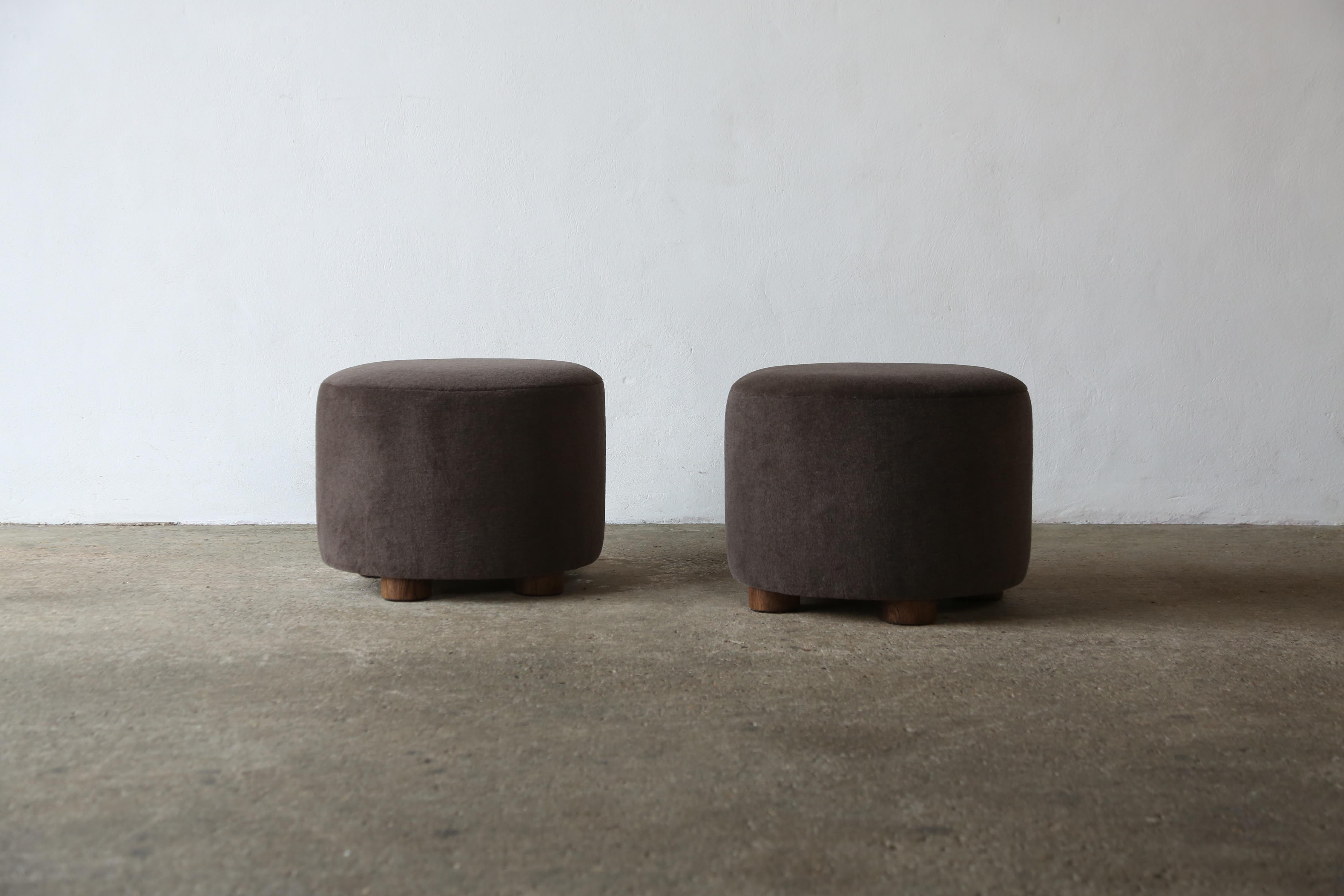 A pair of elegant, modern, low, round ottomans.  Handmade in England.  Newly upholstered in a premium, soft, pure alpaca wool fabric with solid oak feet.    Priced and sold as a pair.  Custom sizes and fabric options available.    Fast shipping