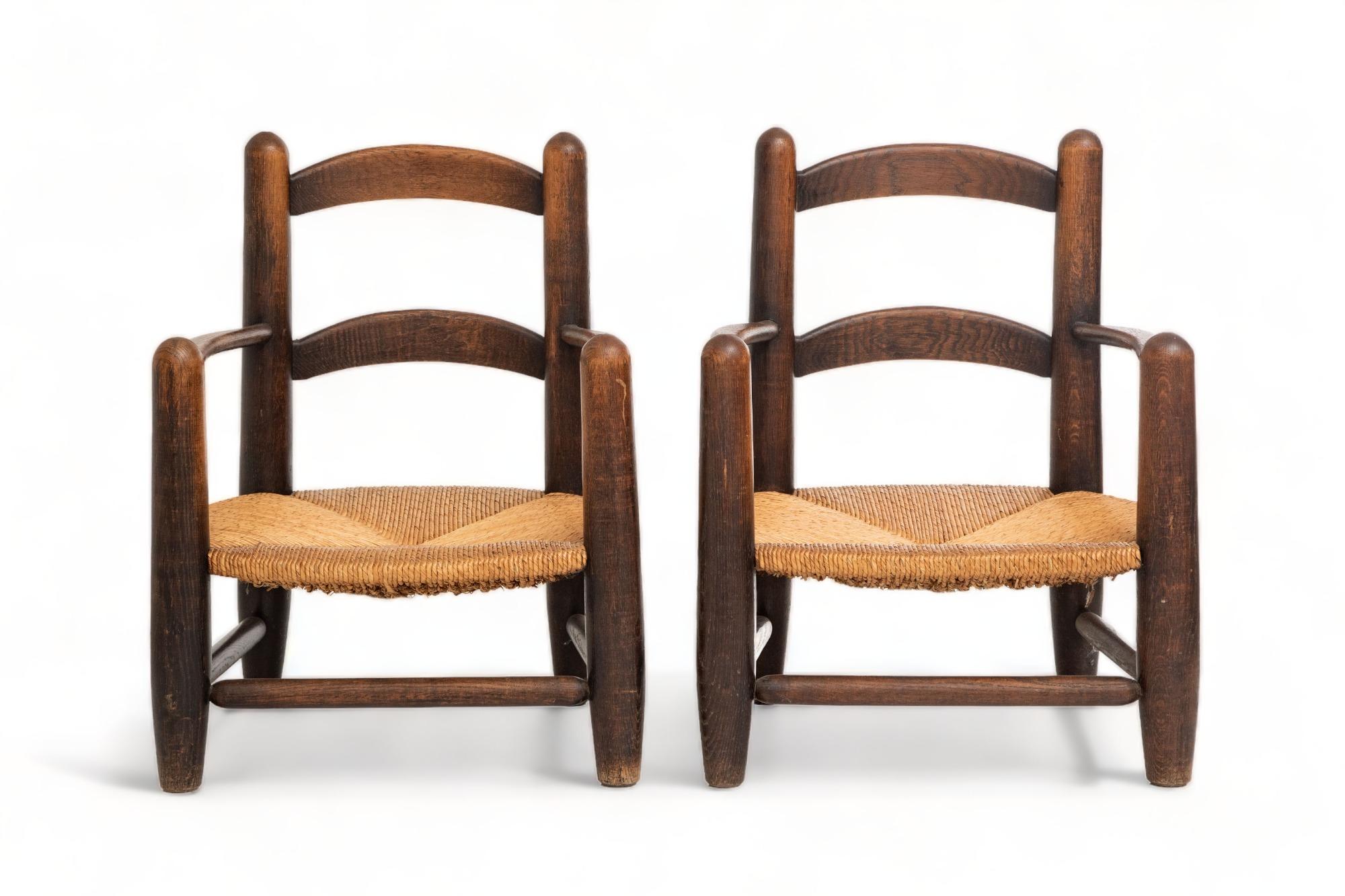 Pair of low rush seats armchairs, France, 1960's
Solid turned oak with outstanding patina and grain 
Handwoven rush seats which are in perfect original condition.
In the manner of Charlotte Perriand
 Used as fireplace armchairs
Ready to ship from