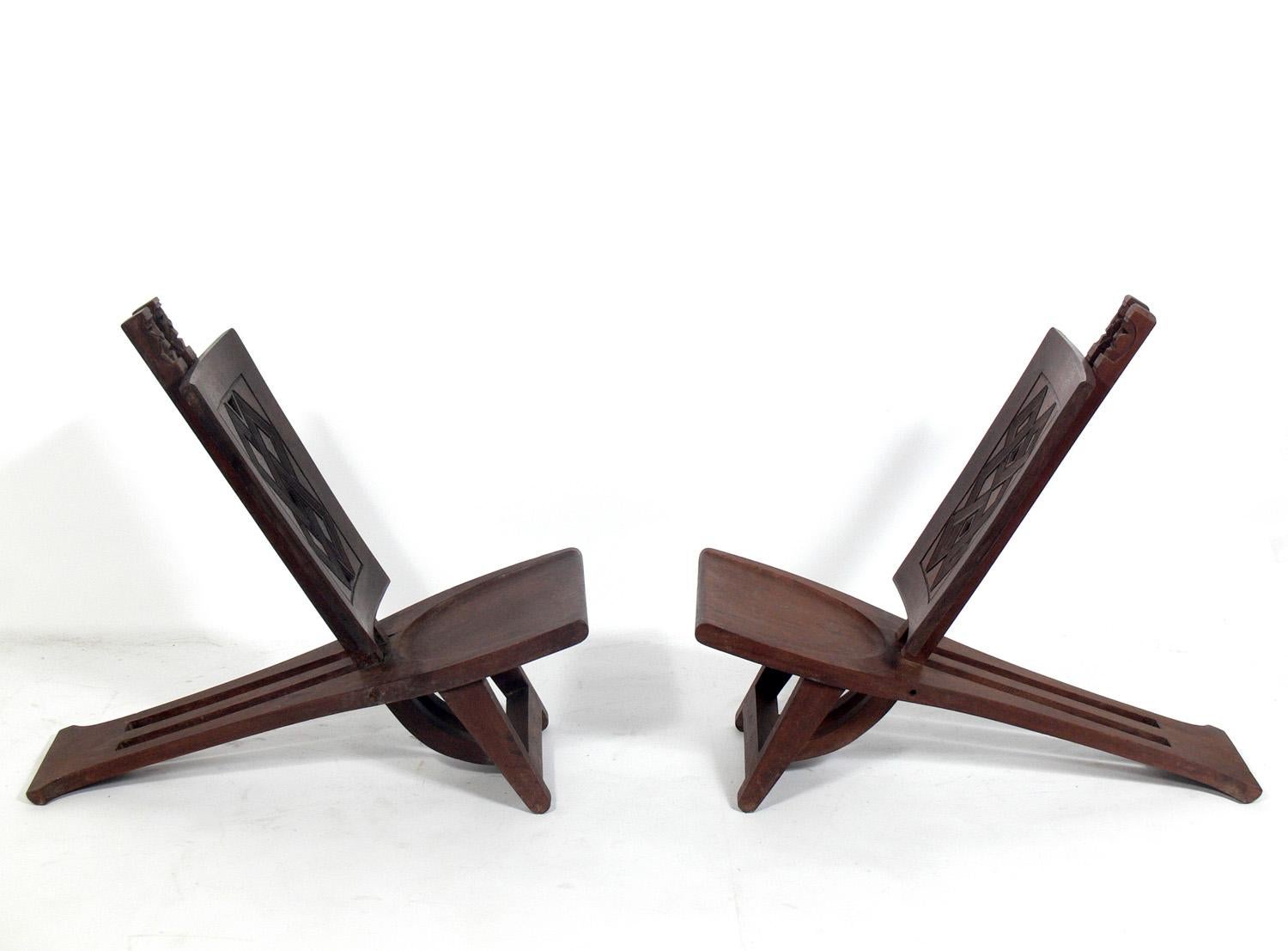 Pair of low slung African lounge chairs, probably from Congol, circa 1960s. Each chair is hand carved and unique and has a slightly different design and dimensions.