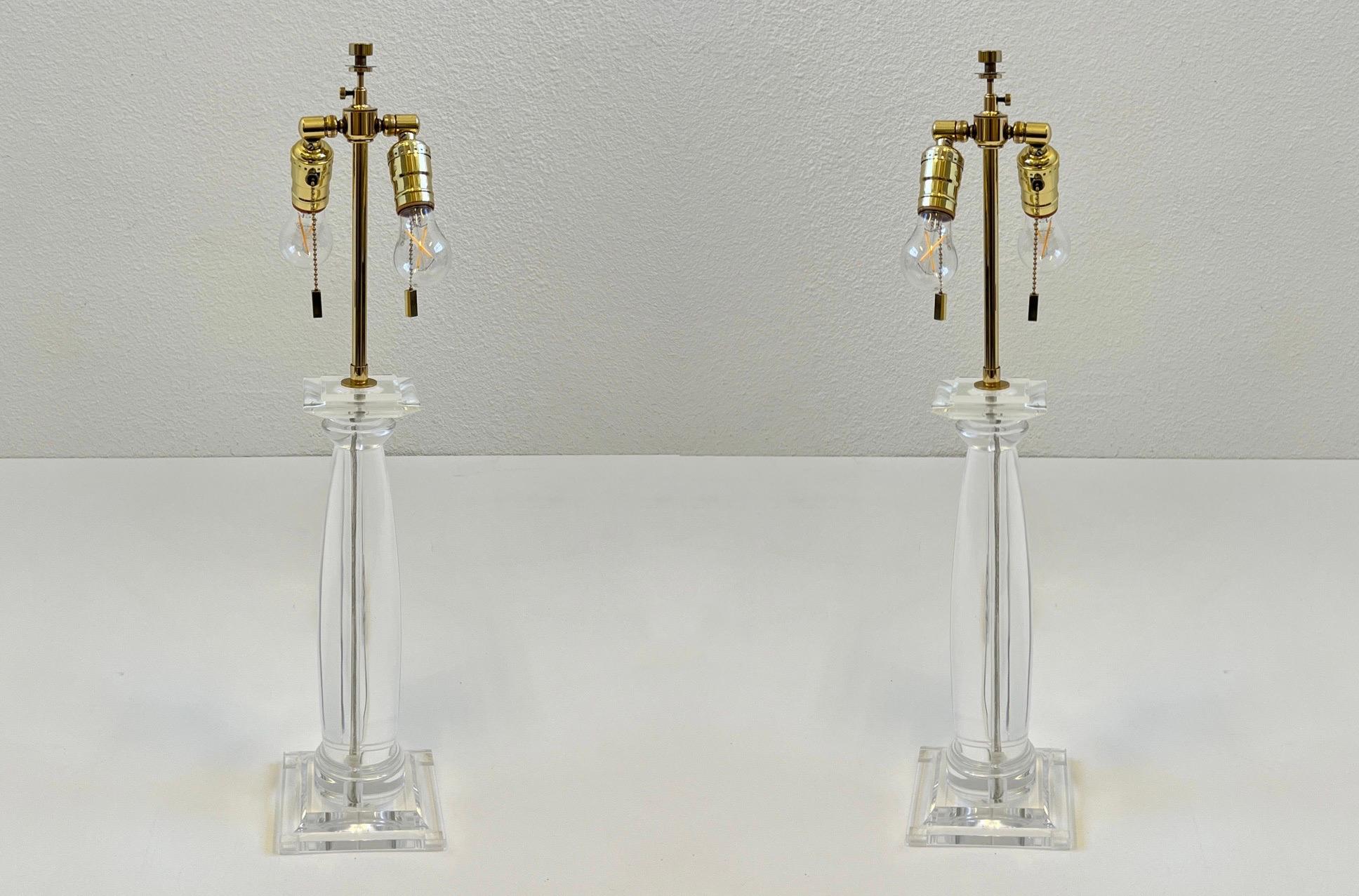 Glamorous pair of 1980s clear lucite and polished brass “Greek Column Table Lamps” by Karl Springer. 

Constructed of solid acrylic and polish brass.
Newly rewired and new shades. 
Each lamp takes two 75w Max Edison bulbs. 

Measurements with