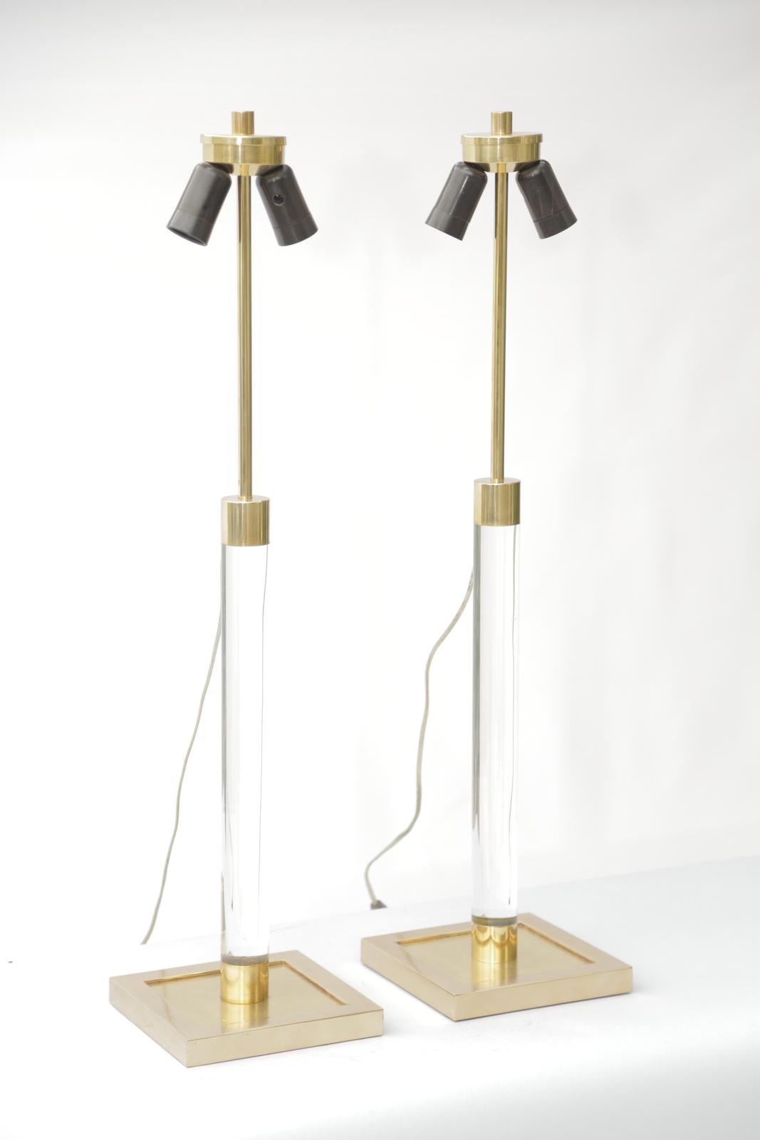 Pair of vintage table lamps, in the style of Karl Springer; each brass-capped round column mounted from a square base of polished brass; the lamps are wired in the French style -- from the top of the lamp. 

Stock ID: D3228.