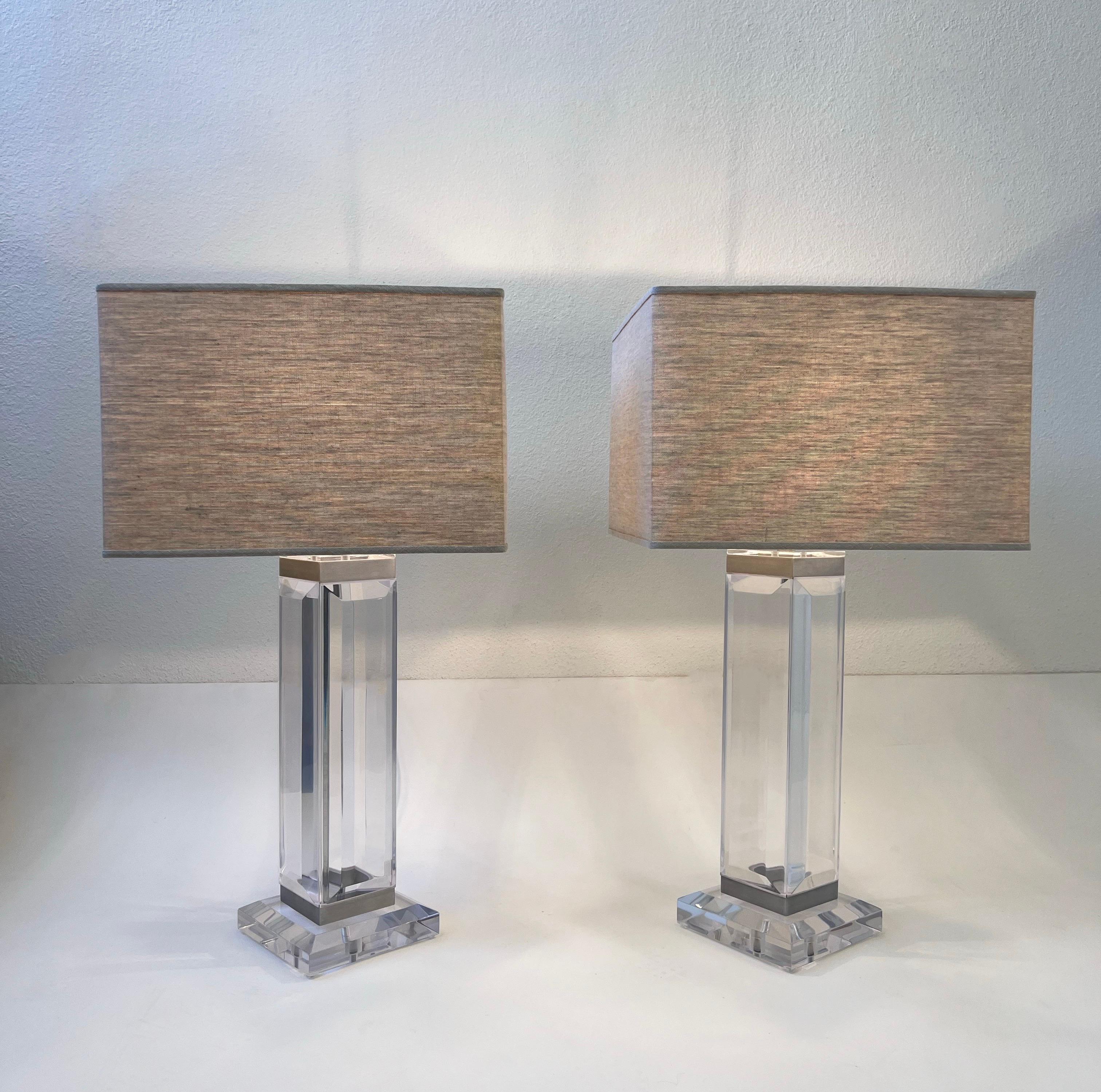 Pair of clear acrylic and brush aluminum with chrome hardware table lamps in the manner of Charles Hollis Jones. 

Beautifully crafted, newly rewired and new shades. They look nice with round or square shades. 
Measurements: 7” wide, 7” Deep, 29.5”