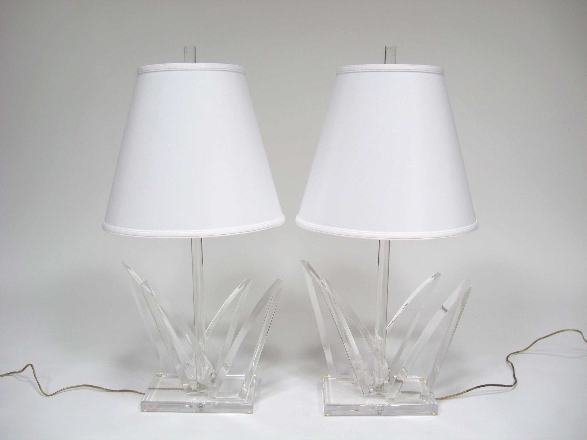 This striking matched pair of Lucite table lamps by Van Teal have style to spare. The dramatic clear lucite bases each have four angular elements and a round central stem that conceals the wire. They are each hand signed on the base.

The lamp bases