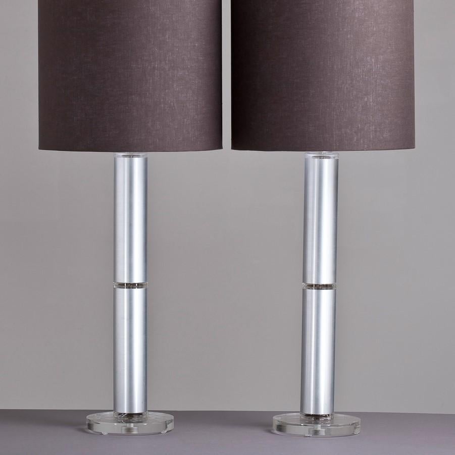 Pair of Lucite and simulated brushed aluminium stemmed table lamps on circular Lucite bases accompanied with linen shades, USA, 1970s.
 