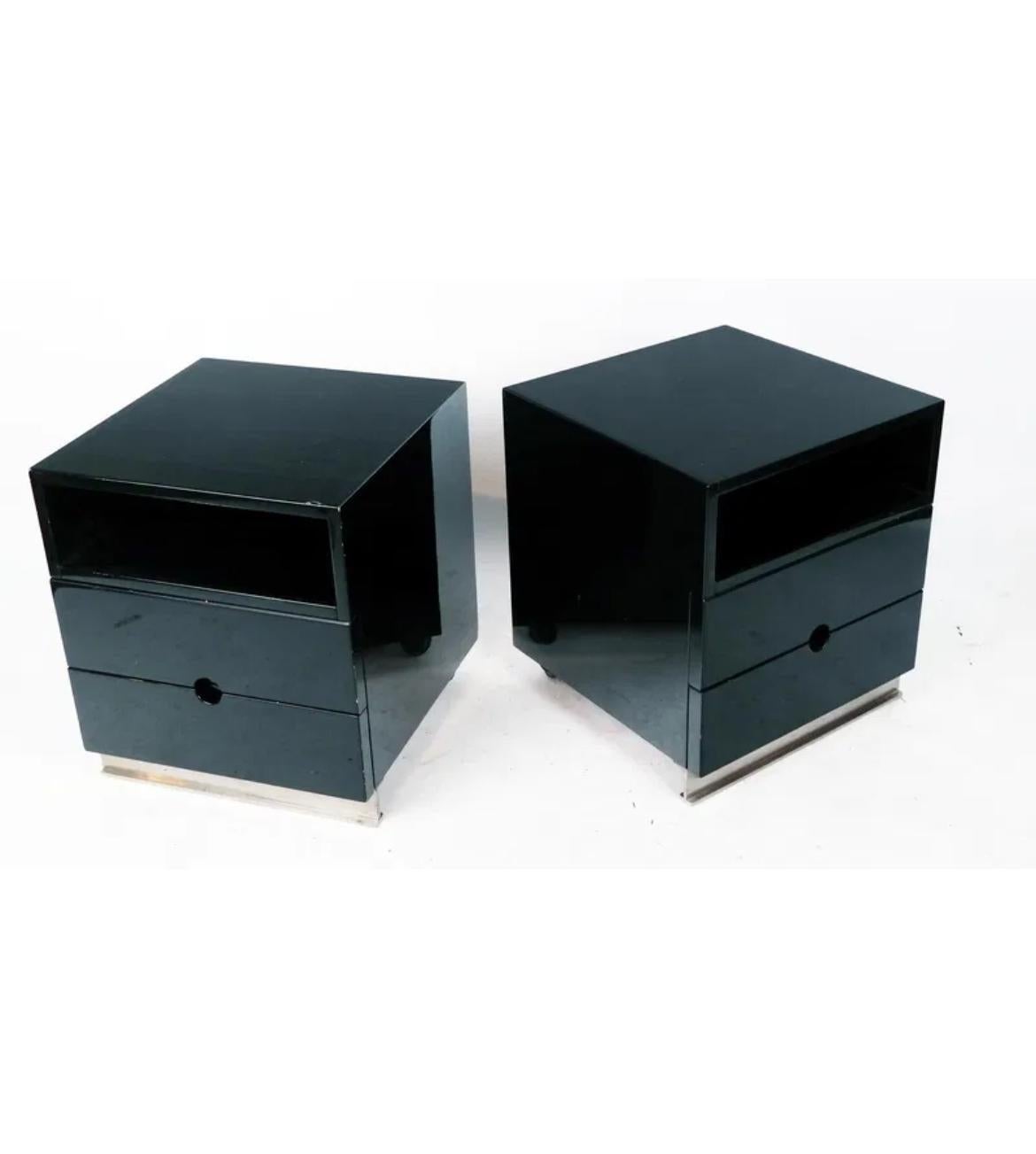 Paire de tables de nuit à 2 tiroirs Luigi Caccia Dominioni en laque noire avec accents chromés. Fabriqué en bois laqué avec des poignées de tiroir rondes et découpées. Il est équipé d'un socle avant et de deux roulettes arrière. Fabriqué en Italie