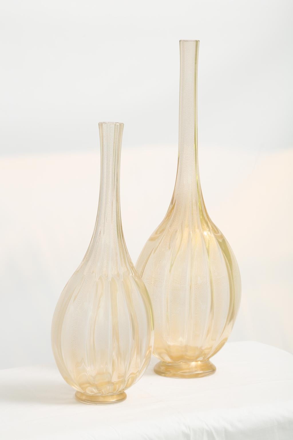 Pair of hand blown bottles, of gold-flecked Murano glass, each having a narrow neck, over ribbed body, on round plinth. Signed 