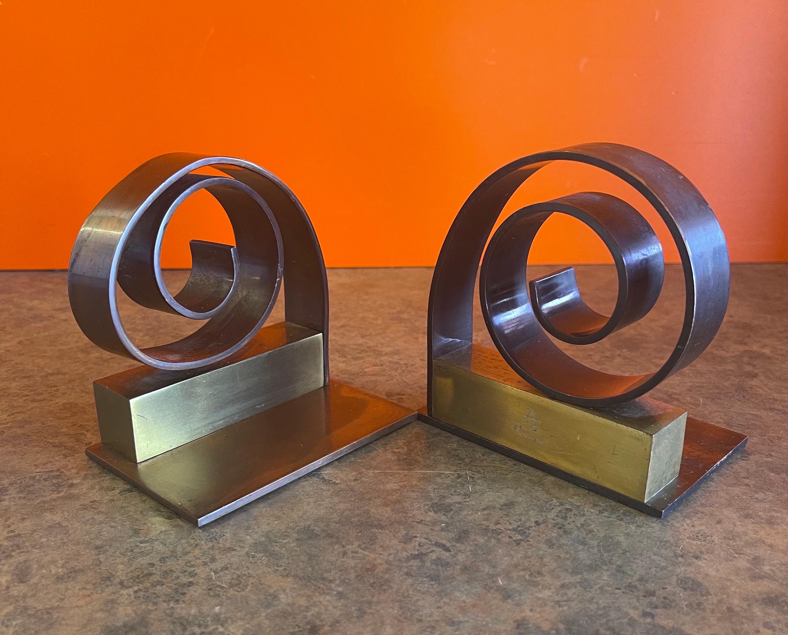 A very nice and hard to find pair of Machine Age / Art Deco / Streamline bookends by Walter Von Nessen for Chase & Co., circa 1930s. These are solid brass & copper bookends with a circular spiral plinth on a square back. The pieces feature felt pads