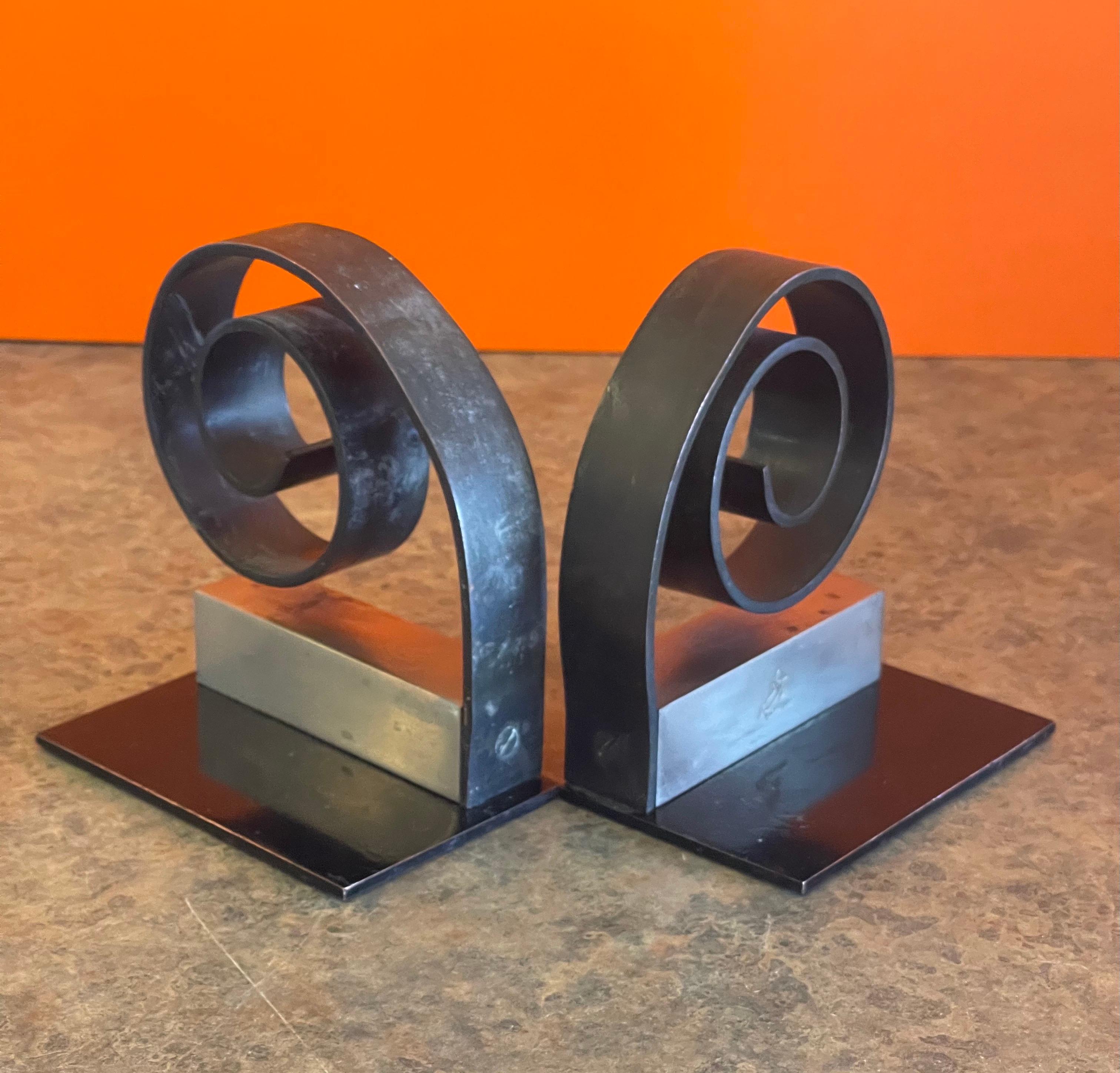 A very nice and hard to find pair of Machine Age / Art Deco / Streamline bookends by Walter Von Nessen for Chase & Co., circa 1930s. These are solid nickel bookends with a circular spiral plinth (painted black) on a square back. The pieces feature