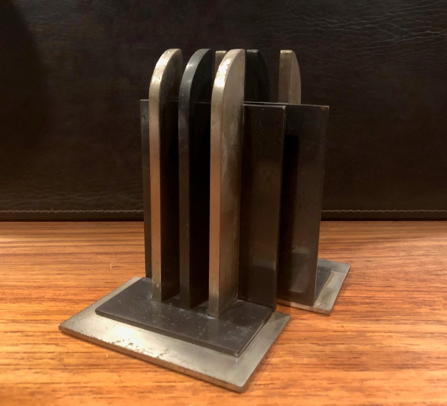 Gorgeous pair of Machine Age or Art Deco bookends by Walter Von Nessen for Chase & Co., circa 1930s. These are solid brass bookends with three perpendicular rounded beams along a square back and have a satin nickel and blackened nickel finish. The