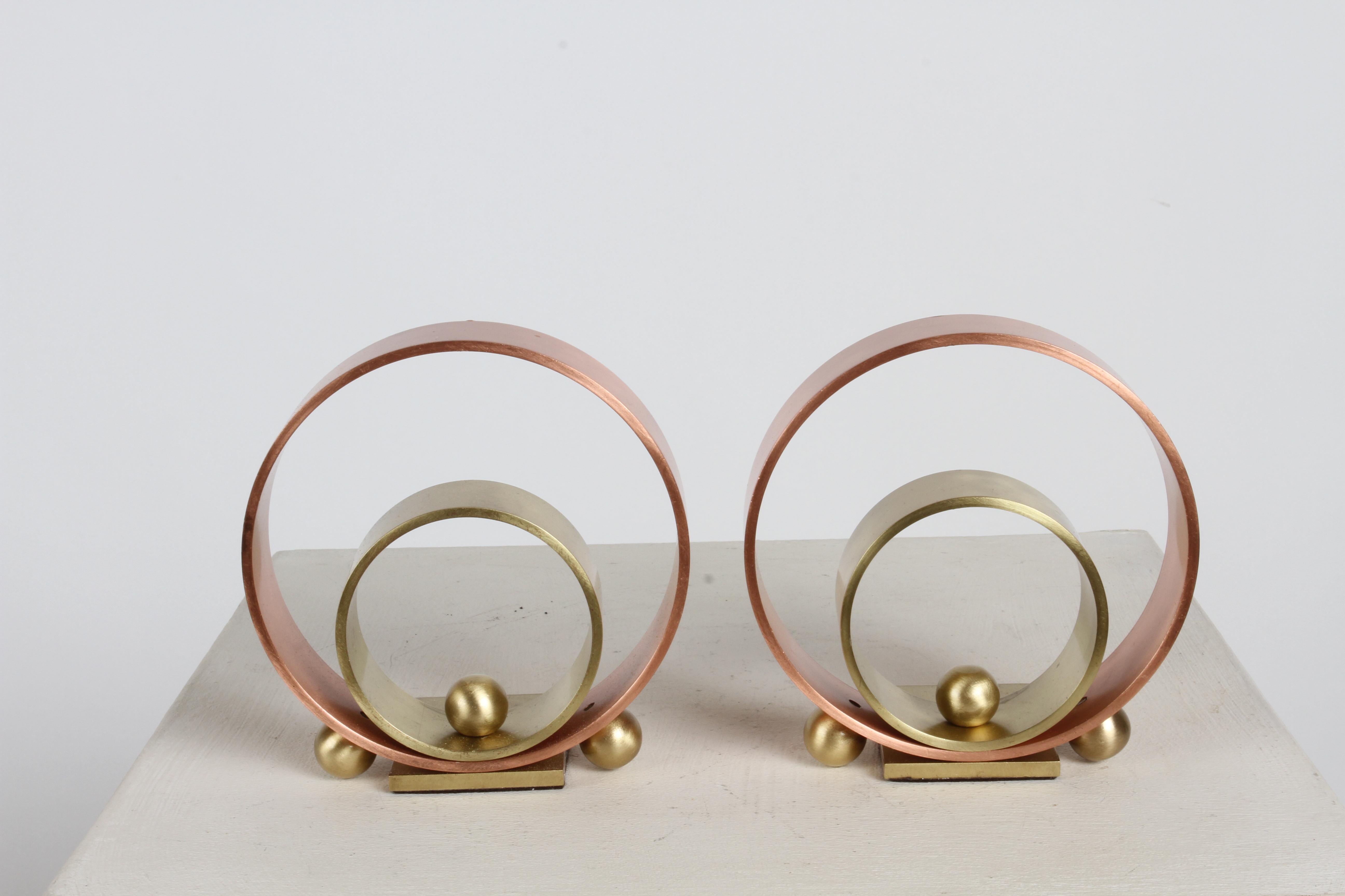 A pair of Art Deco bookends by Walter Von Nessen feature two concentric rings of brass and copper with three sphere accents on each. These bookends are a great example of  the Machine Ages influence on Art Deco in America. Recently polished. Marked