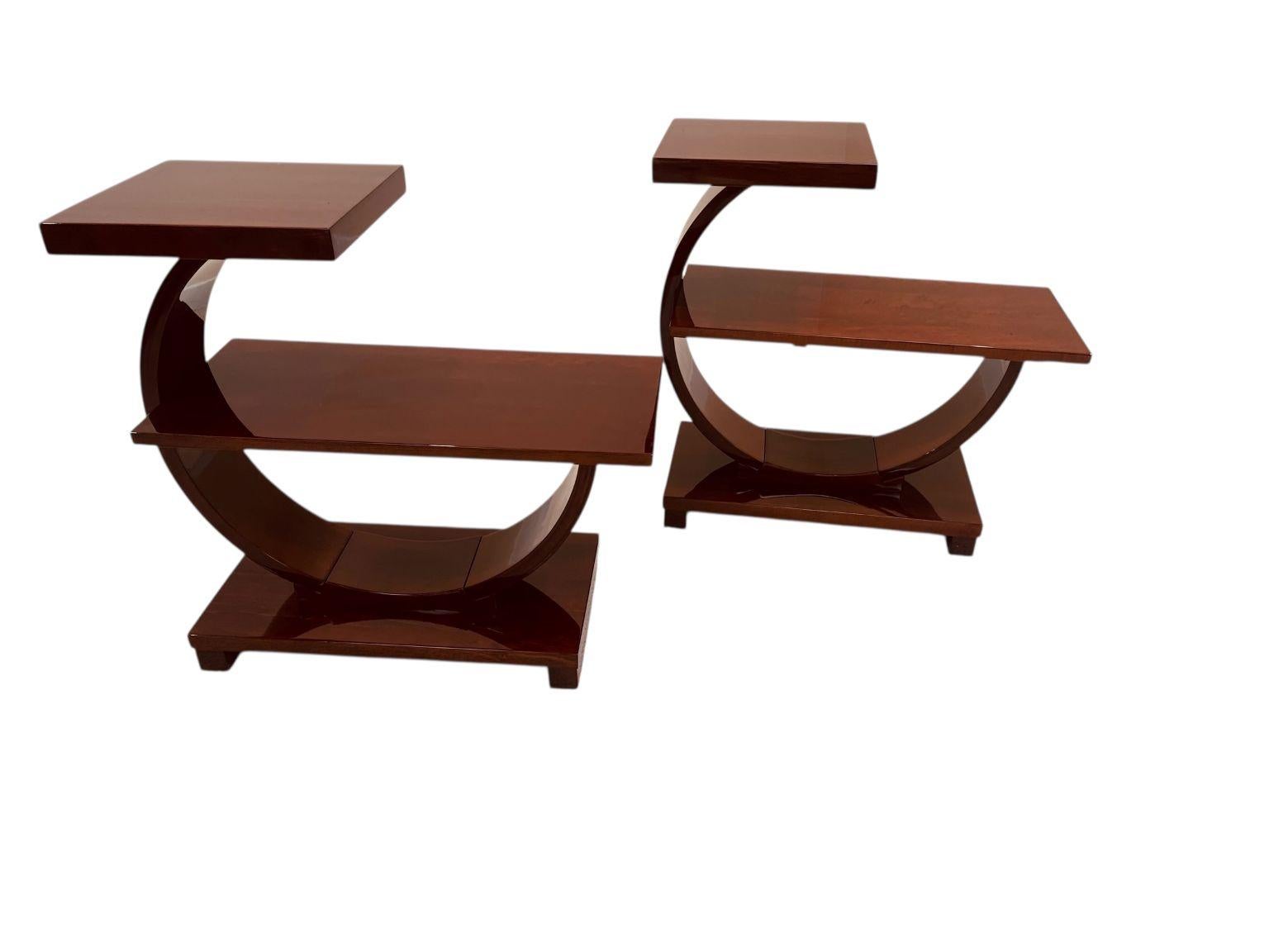 Pair of American Art Deco side tables retailed and made by the Modernage Furniture Company. A three-quarter circle holds a long shelf with a smaller shelf at the apex. They are known in the trade as a “G” table because of their form. Reference in