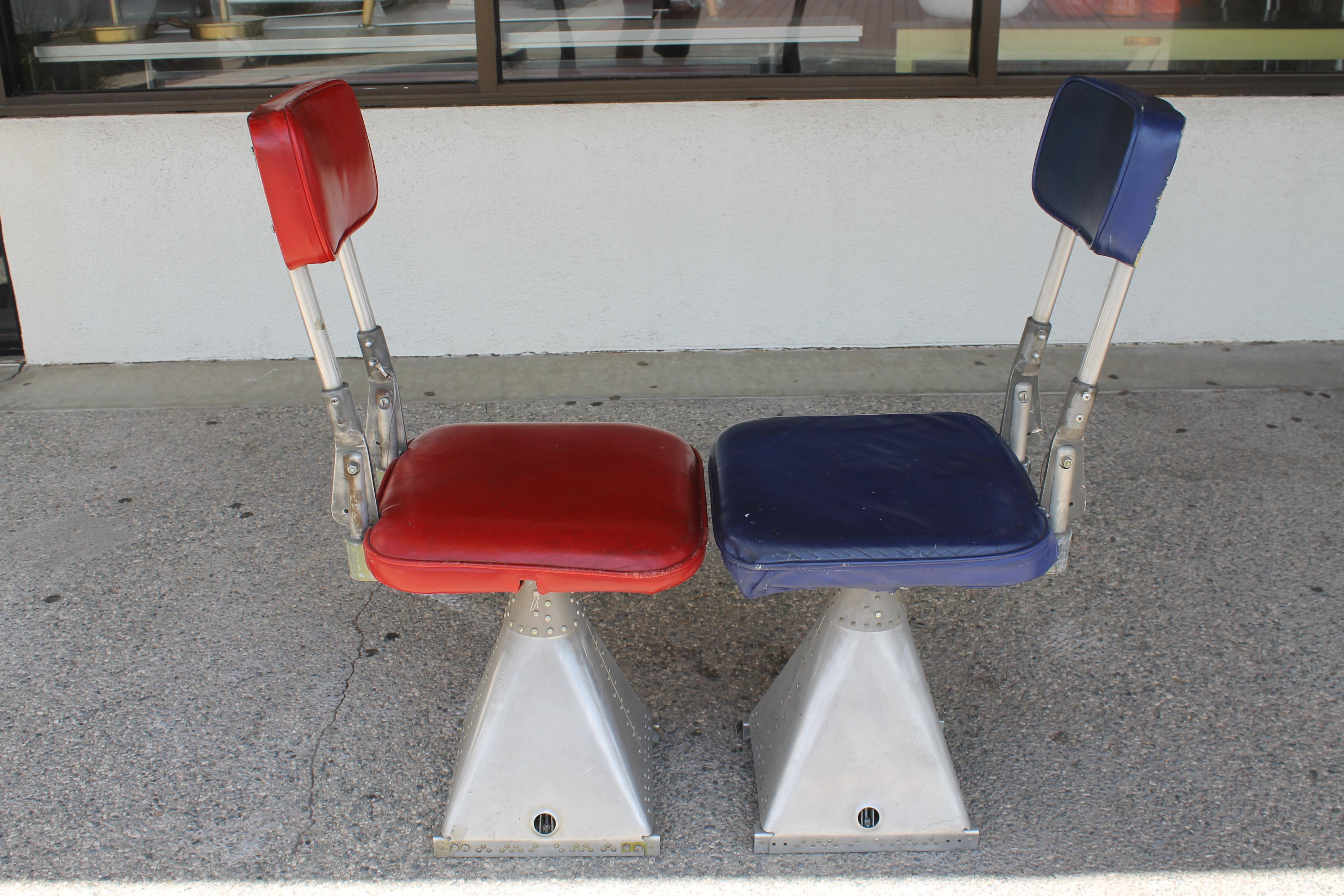 Pair of aluminum machine age airline chairs. Each chair sits on a riveted aluminum base. With cushions upright they measure about 37