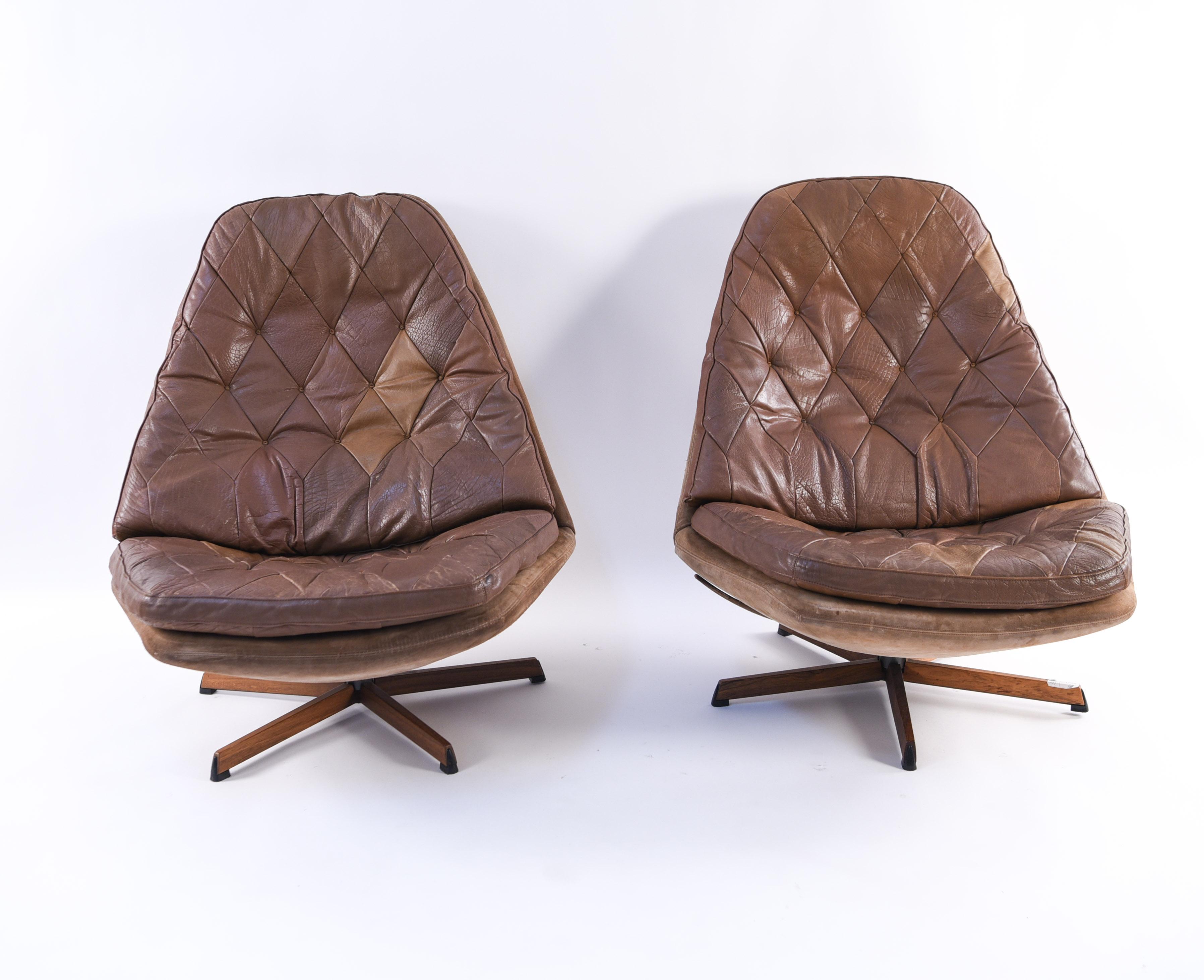 A pair of Danish midcentury swivel high back lounge chairs by esteemed producer Madsen and Schubell, model MS 68. The chairs are upholstered in a brown leather, the tufted design on which creates a pleasing diamond pattern.
