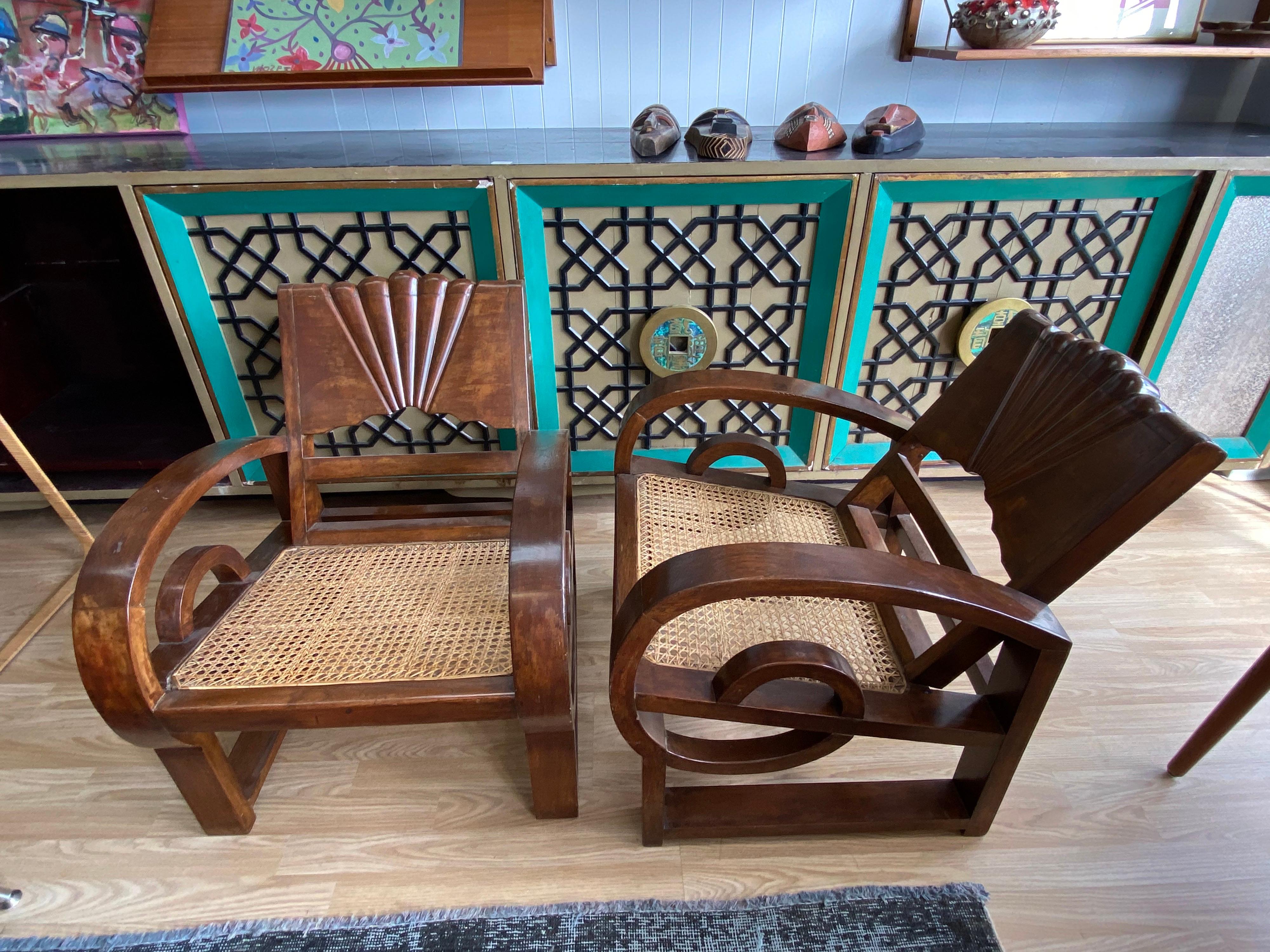 Unique pair of vintage Madura side chairs made of Indonesian teak wood with rattan seats, curved lopping arms and feature accented motif backs. These early 20th century side chairs are the perfect accents to any space. With age-appropriate wear,