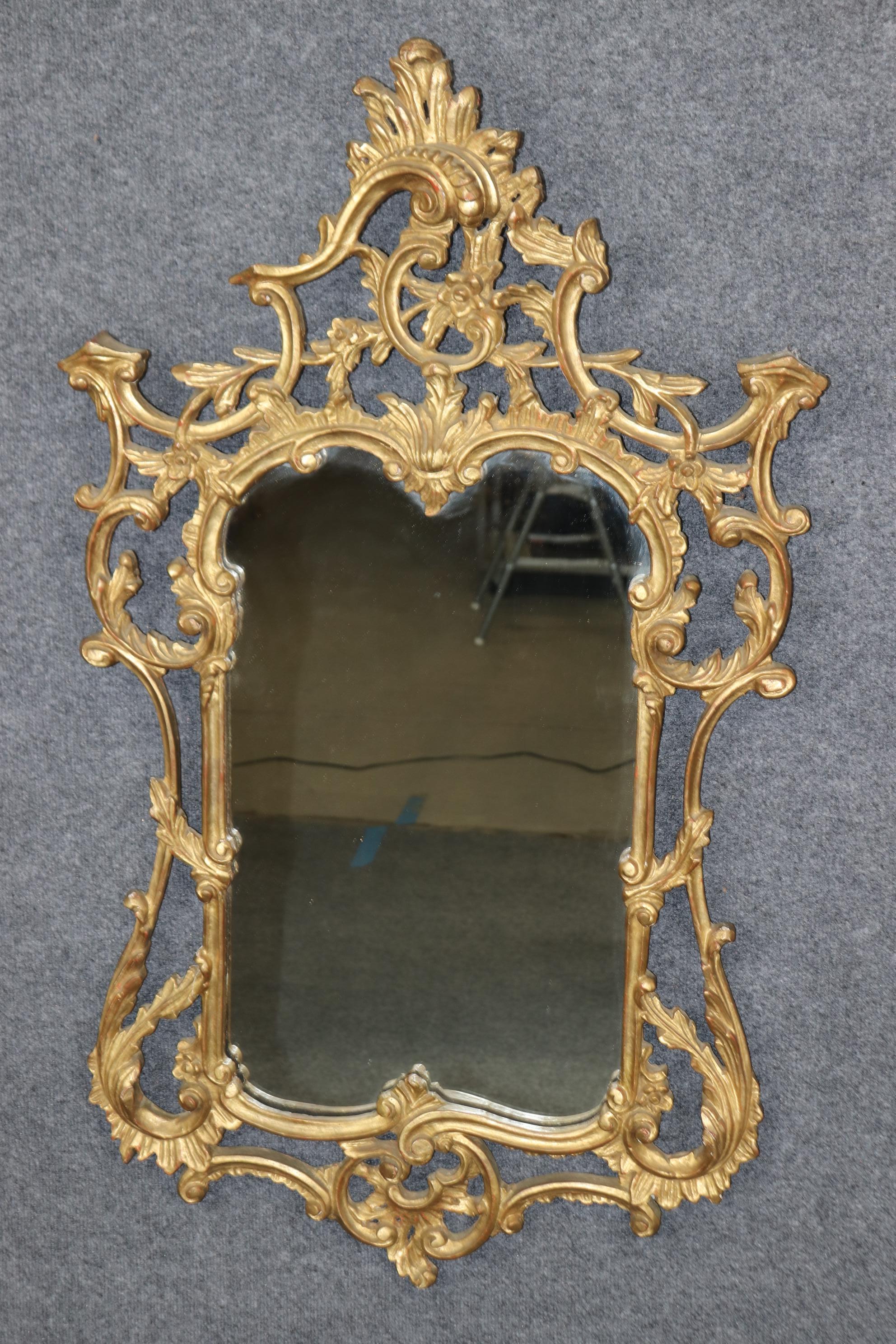 This is a superb pair of carved wood, not gesso, Italian-made mirrors with genuine parcel gold leaf frames and clear mirror plate glass mirrors. The mirrors are a superb example of French Louis XV or possibly Rococo styling and have a time-worn