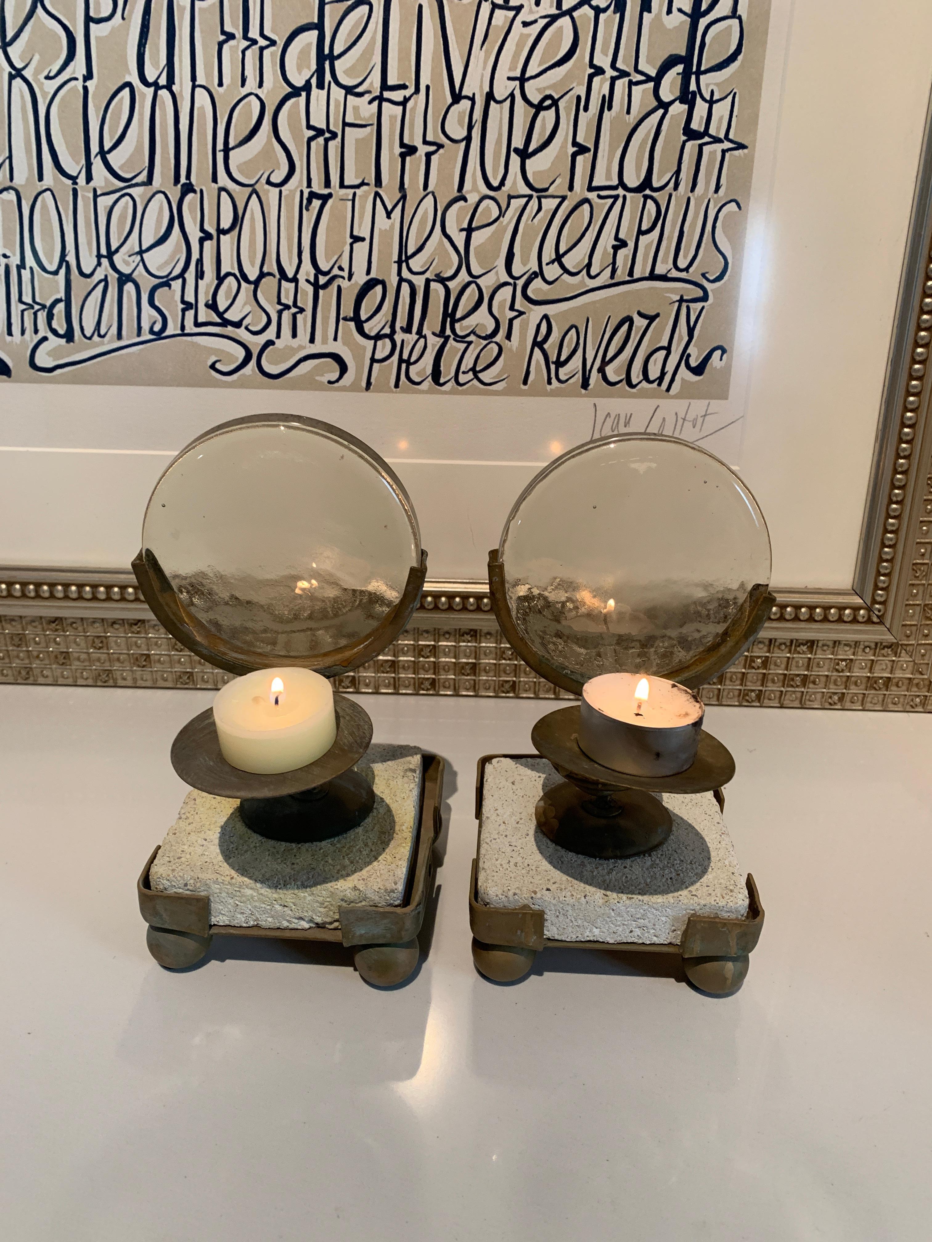A pair of primitive Industrial metal frames on a stone stand with a thick piece of glass to magnify candle light. These are very unique pieces to be used as candleholders / decorative pieces. The stone is very porous and rustic, as are the stands