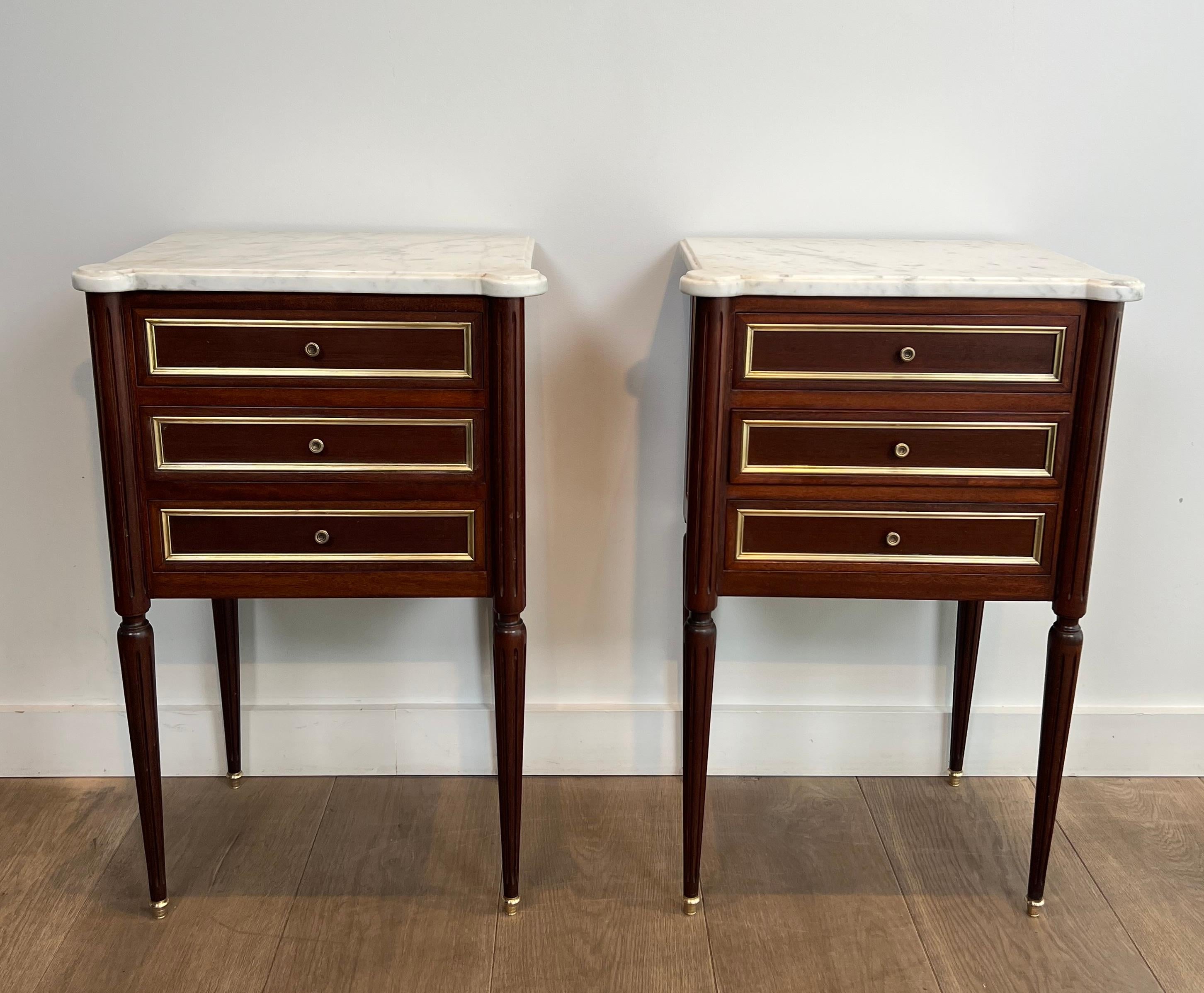 Questa bella ed elegante coppia di tavolini o comodini è realizzata in legno e ottone con piani in marmo di Carrara. Questi tavoli hanno 3 cassetti. Si tratta di un'opera francese nello stile della Maison Jansen. Circa 1940