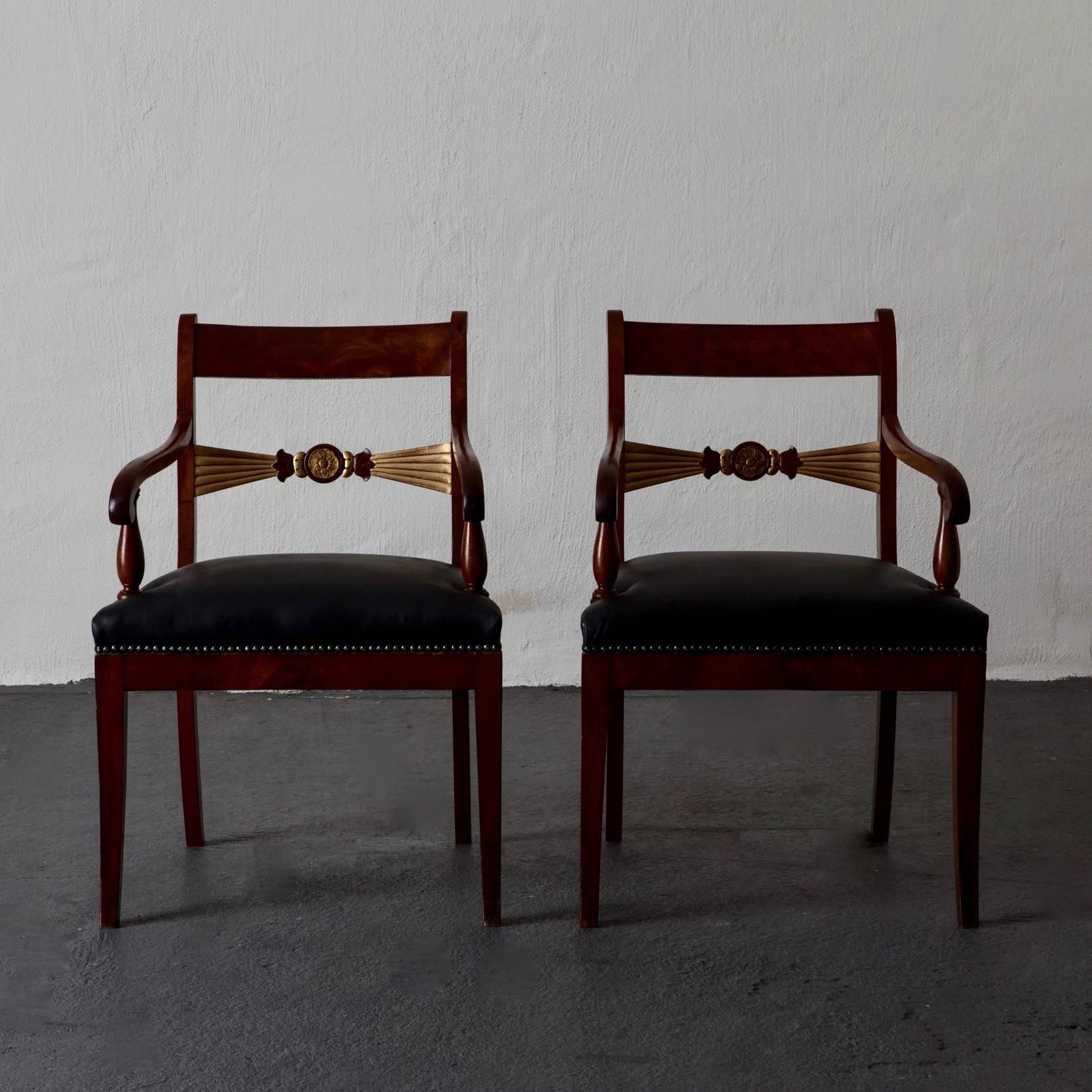 Pair of mahogany armchairs with gilded details 19th century black leather, England. A pair of armchairs made in England during the Regency period 19th century. Frame made in mahogany with gilded details. Upholstered in black leather. Restored.