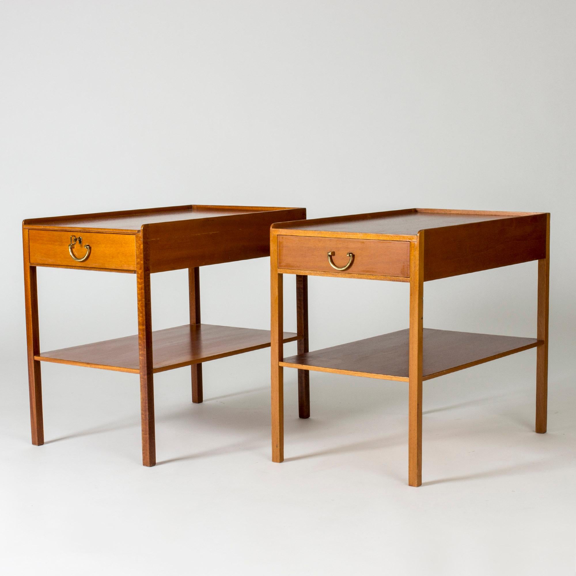 Pair of elegant bedside or side tables by Josef Frank, made in mahogany. Clean, slender lines, single drawers and neat brass handles.