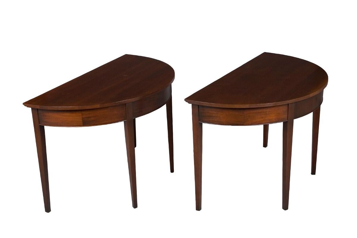 This great looking pair of solid mahogany demilune hall tables was made in the US sometime in the 1950s. They boast an attractive medium brown color and sturdy construction. Their fairly large size makes them ideal to fill a number of spaces within