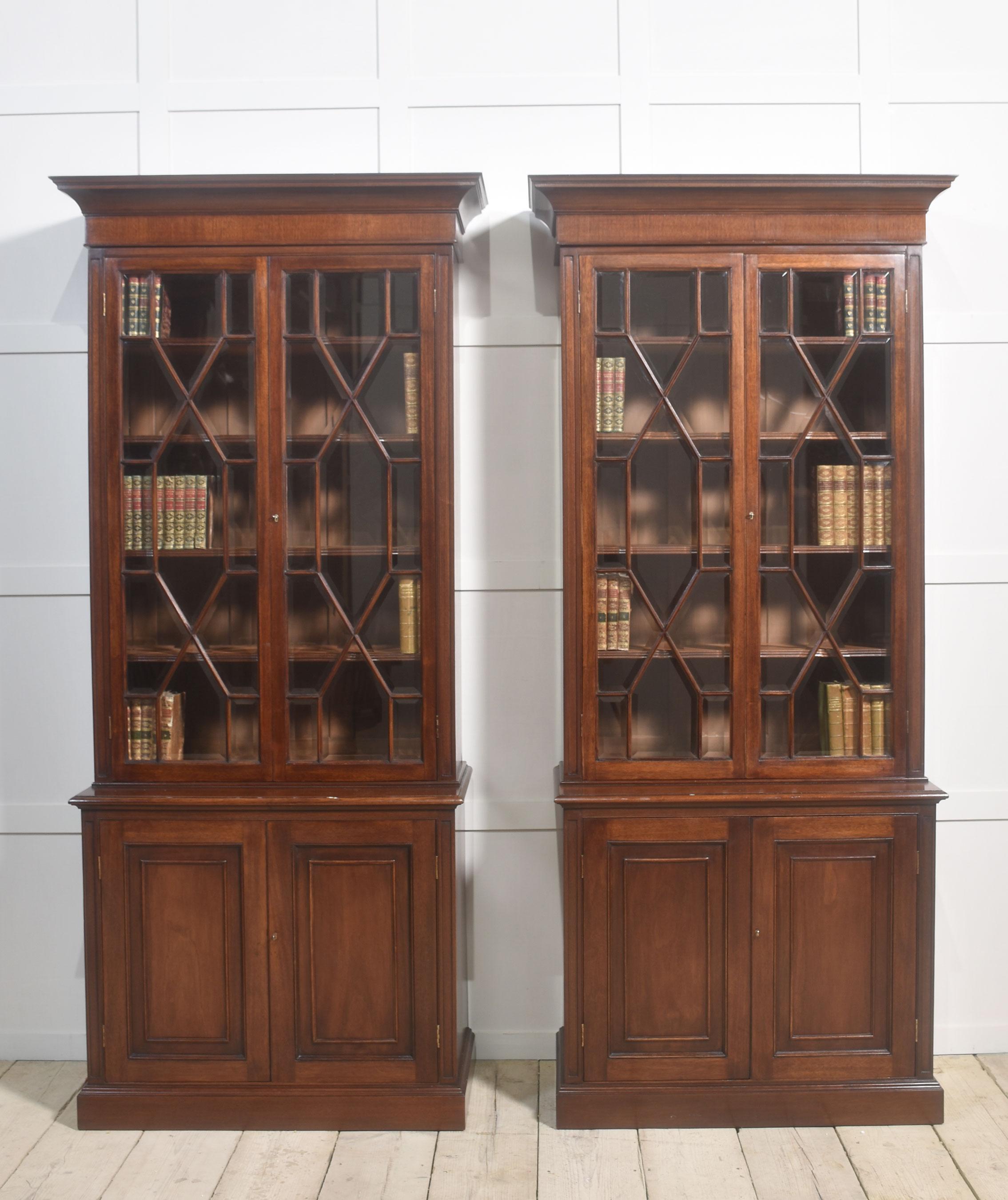 Coppia di librerie vetrate in mogano, con cornice intagliata e modellata sopra due grandi porte vetrate astragali con apertura in vetro smussato per rivelare l'interno a ripiani regolabili. La sezione di base è dotata di una porta rivestita che si