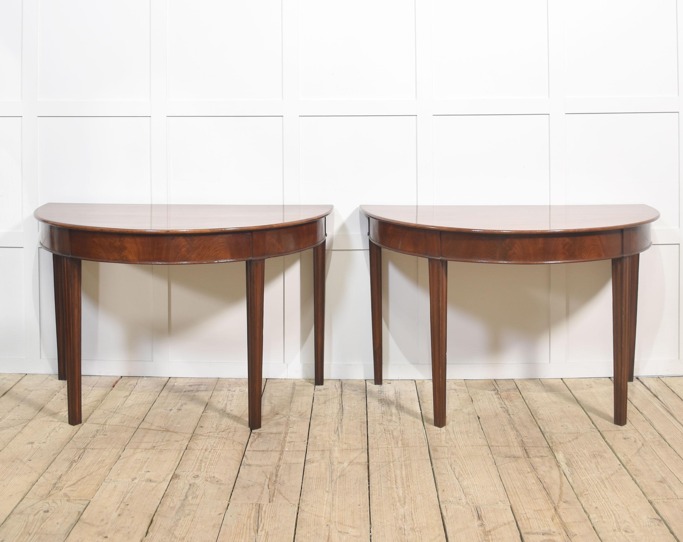 Paire de consoles démilunies en acajou, datant du 19e siècle. Chaque table présente un plateau en acajou magnifiquement figuré avec une patine chaude et polie et d'élégants pieds fuselés, offrant un design raffiné mais understated.
La paire peut
