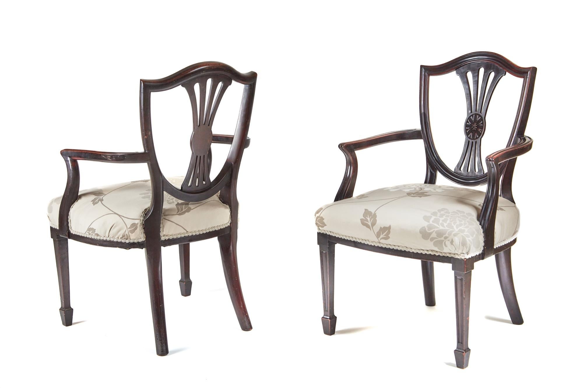 A pair of mahogany 'Hepplewhite style' elbow chairs, with a shield shaped back and a pierced reeded central splat, nice reeded shaped arms, the overstuffed wide seats have been recovered in a very attractive fabric, the front legs are square