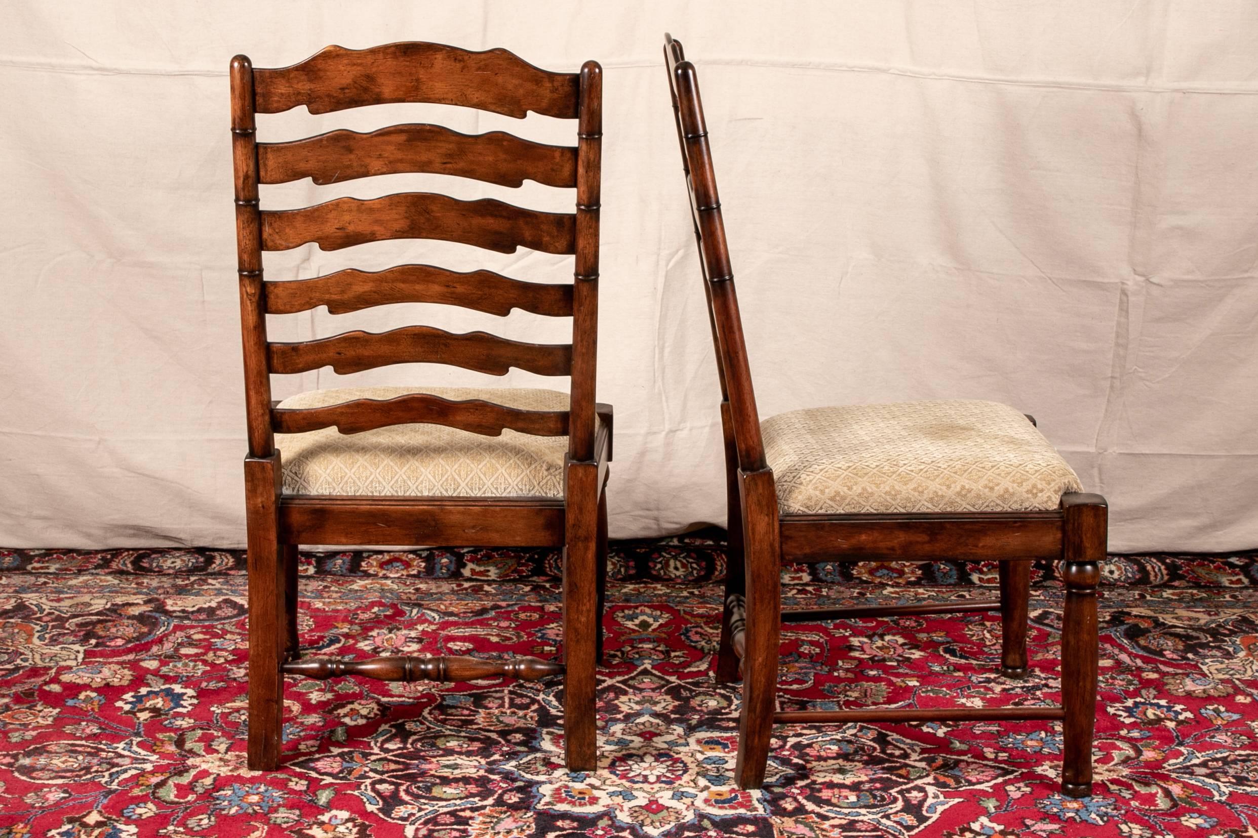 Pair of ladder back chairs, mahogany, each with six shaped back rails on turned supports, with turned front legs and splayed back ones. Side stretchers and a turned back stretcher, seats upholstered in a pale taupe cut velveteen fabric.