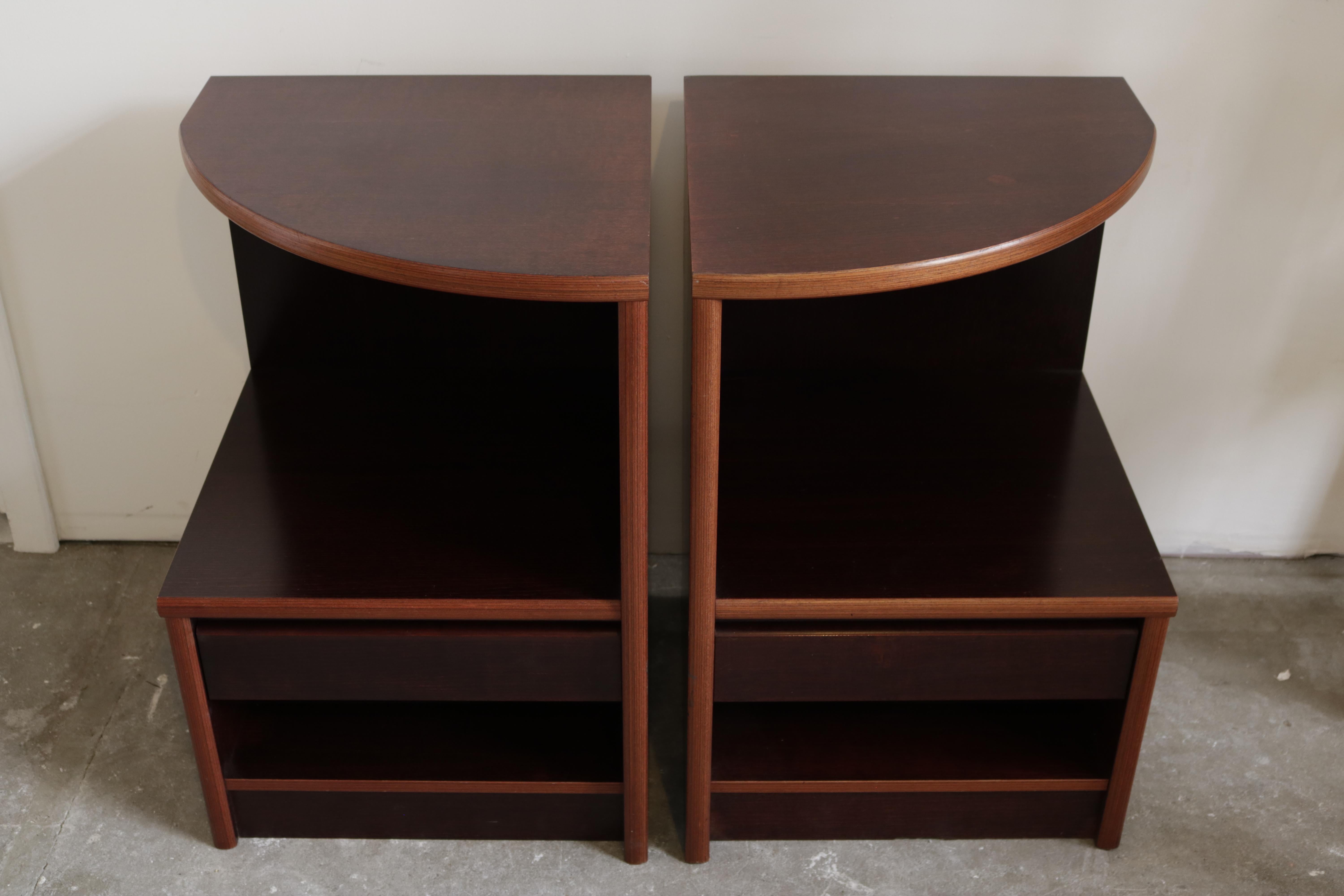 This pair of asymmetrical nightstands features one drawer and a shelf under it.
They are made of dark mahogany with lighter mahogany trims.