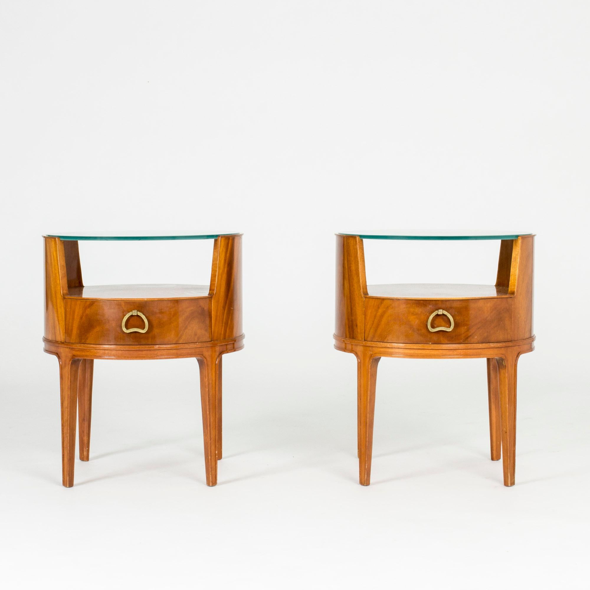 Pair of beautiful bedside tables by Axel Larsson, with pyramid mahogany veneer, green tinted glass tops and sculpted brass handles. The glass tops have an etched checkered pattern.