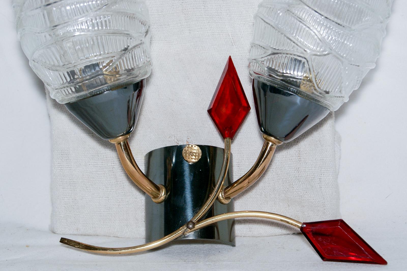 An elegant pair of midcentury wall sconces by Maison Arlus, 1950s-1960s, France.

These midcentury modern, 1950s-1960s originals feature two conical glass shades mounted on an asymmetrical curved double brass structure with charming ruby red lucite
